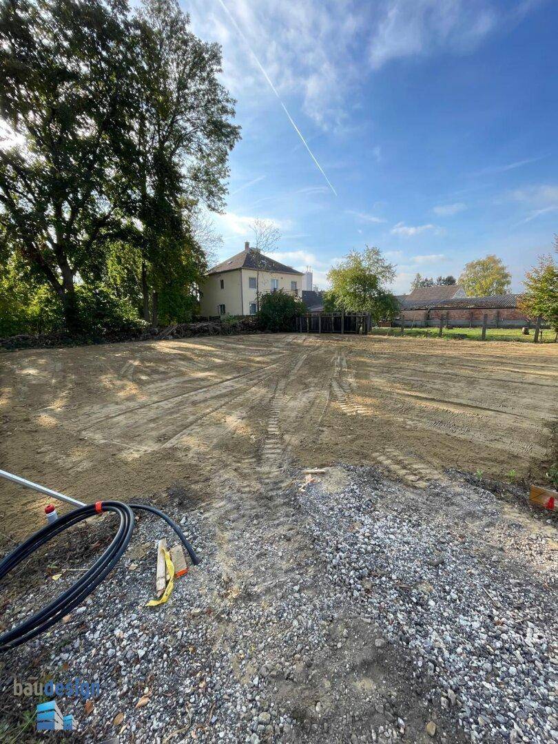 Weitläufiges Baugrundstück mit Erdarbeiten und sichtbaren Versorgungsleitungen im Vordergrund.