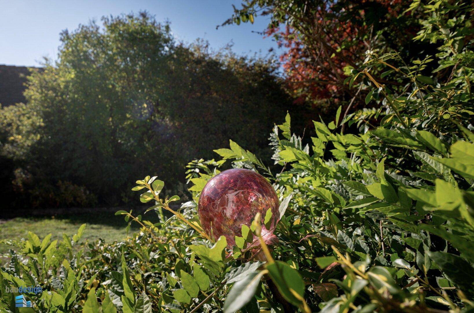 Nahaufnahme eines Busches mit einer dekorativen Glaskugel im Garten.