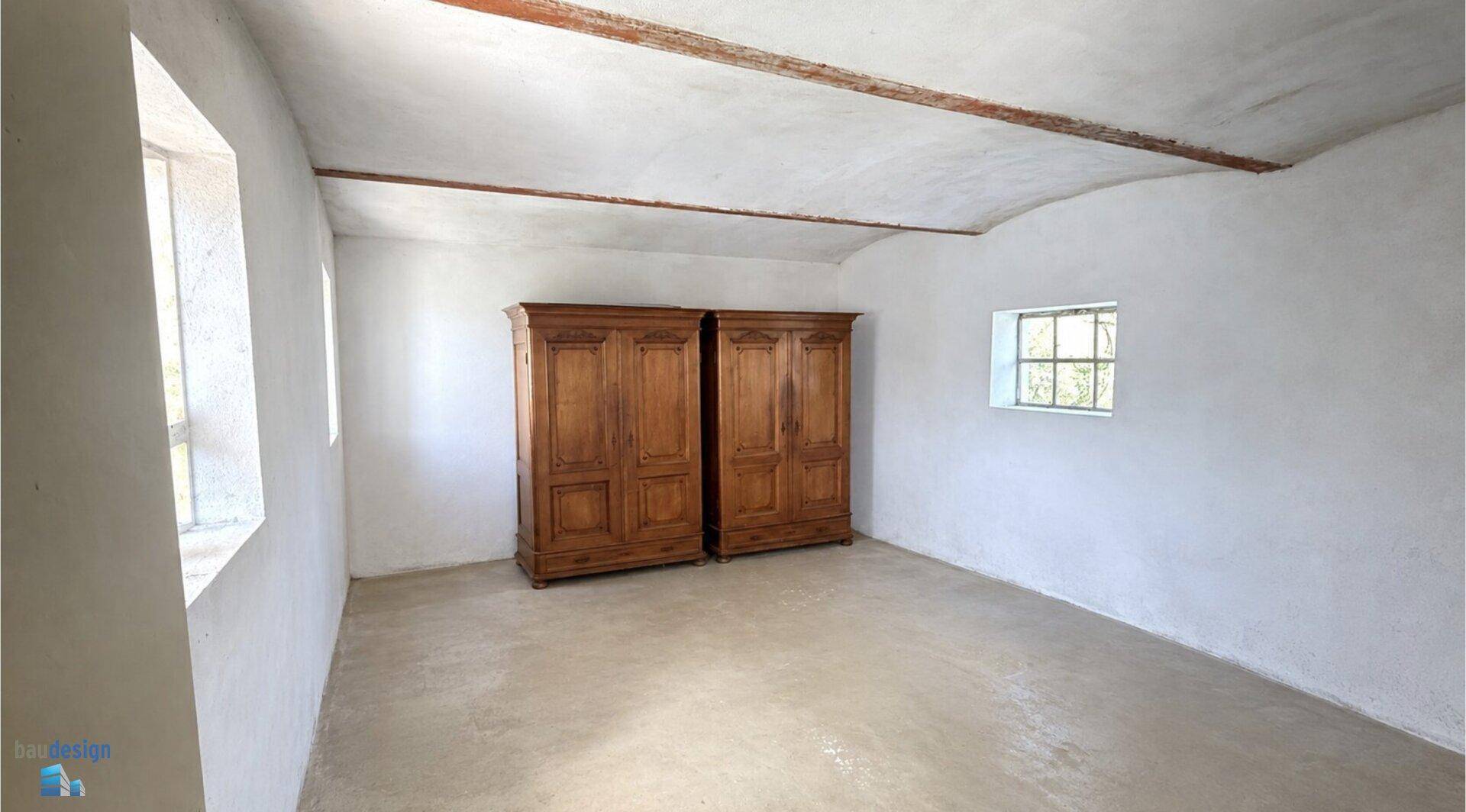 Großer, leerer Raum mit Holzbalken und zwei antiken Holzschränken.