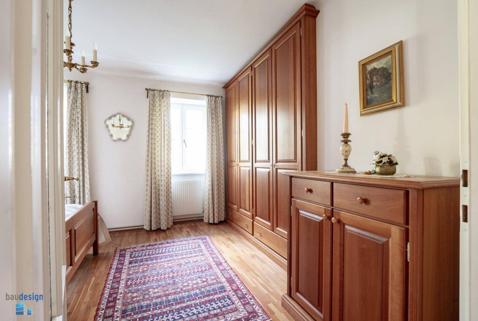 Gemütliches Schlafzimmer mit Holzboden, großem Kleiderschrank und Fenster.