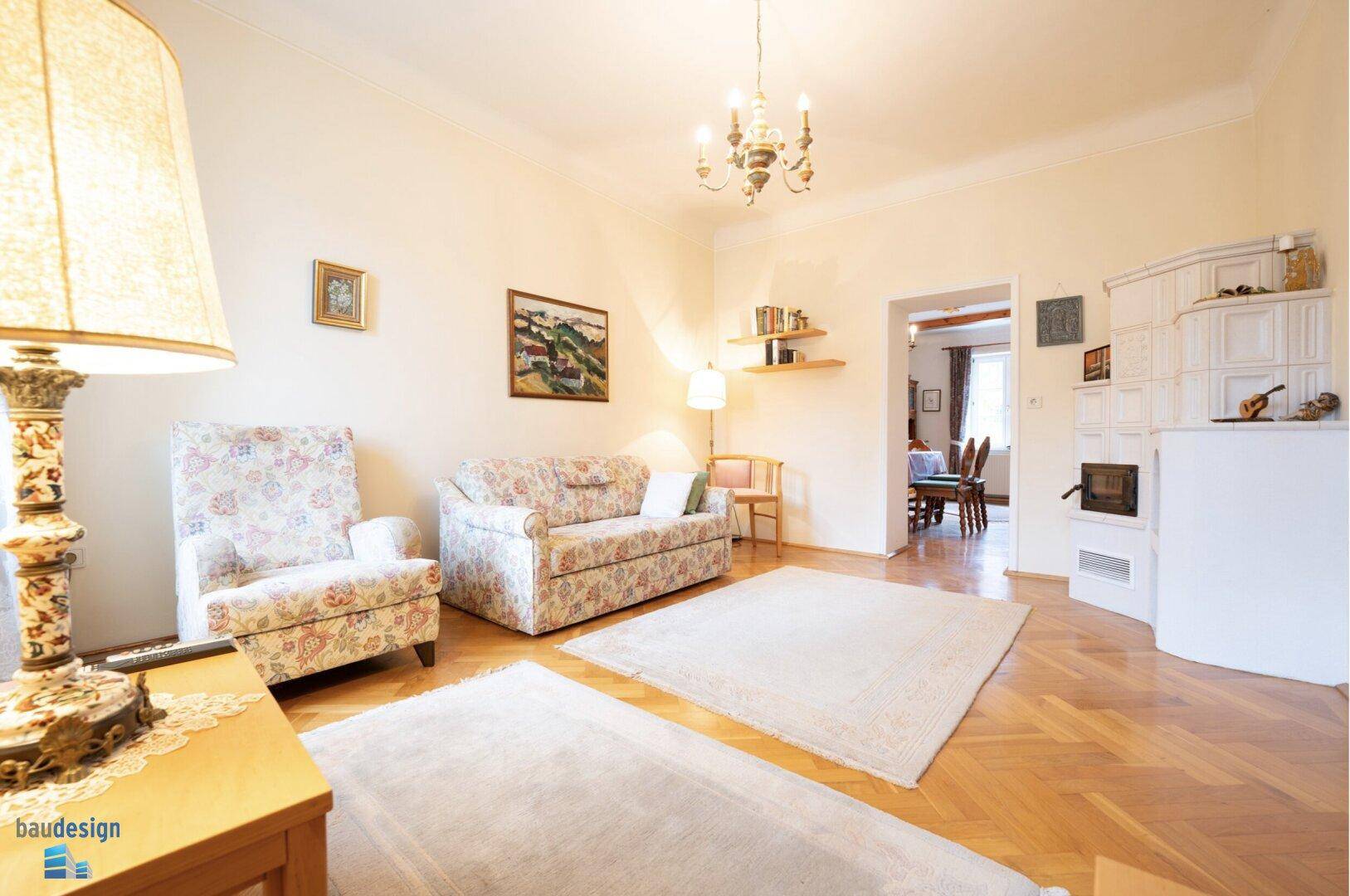 Geräumiges Wohnzimmer mit Kachelofen, Parkettboden und Zugang zum Essbereich.