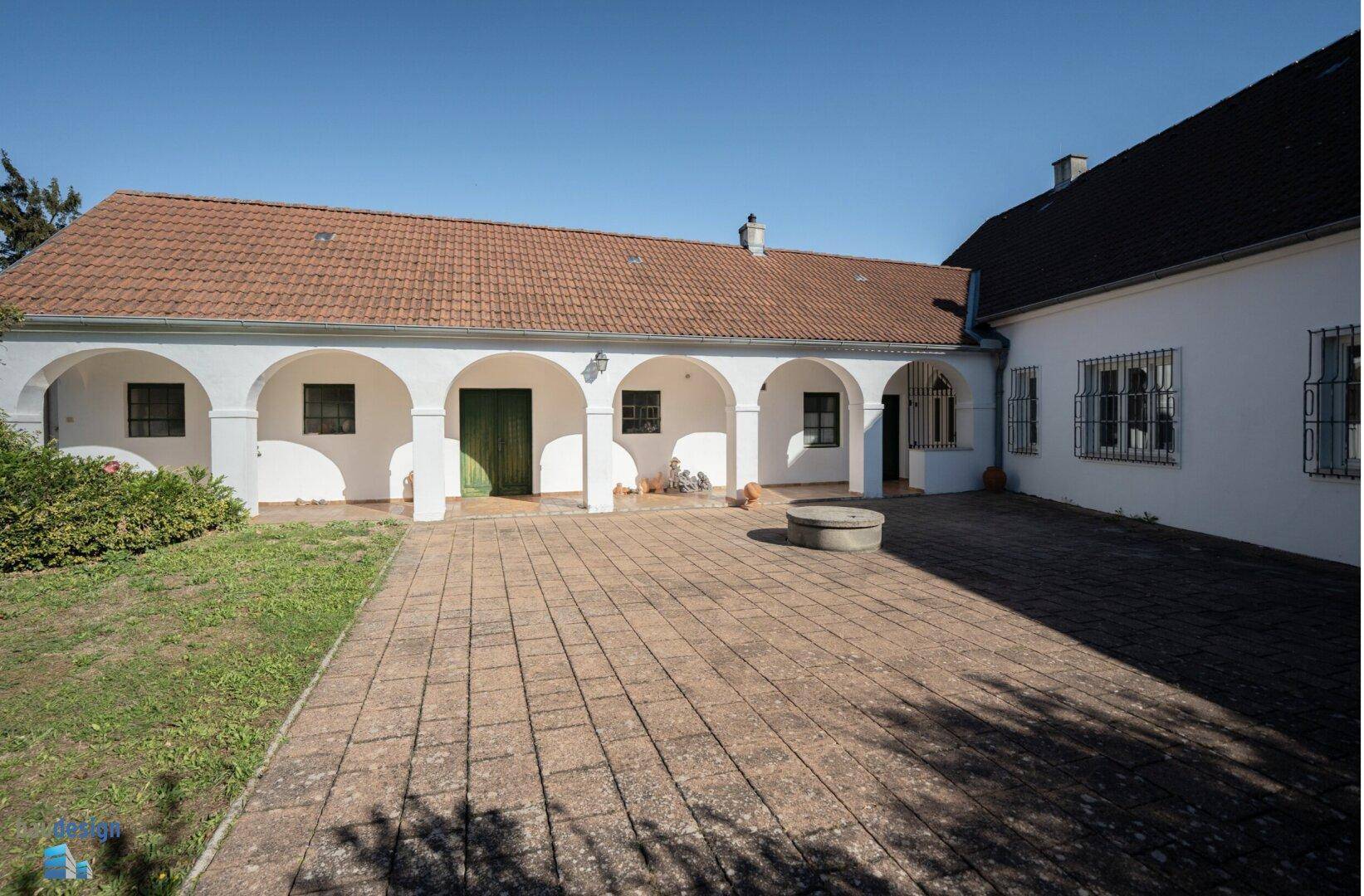 Weitläufiger Innenhof mit Arkaden, gepflastertem Bereich und Grünfläche.