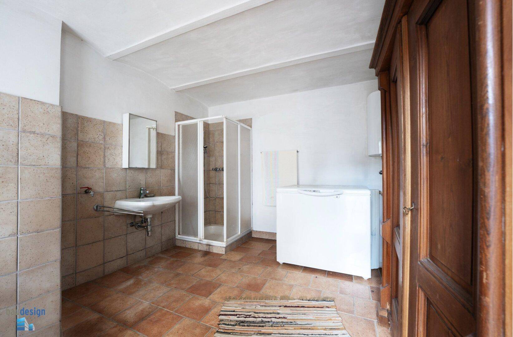 Geräumiger Hauswirtschaftsraum mit Dusche, Waschbecken und Terrakottafliesen.