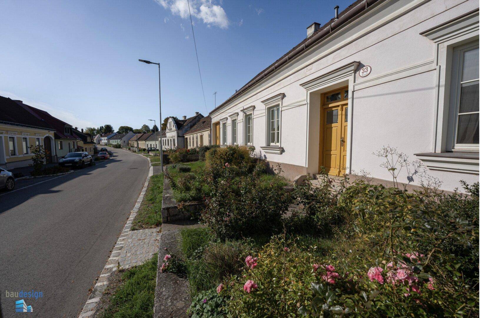 Seitenansicht des traditionellen Hauses mit Vorgarten und ruhiger Dorfstraße.