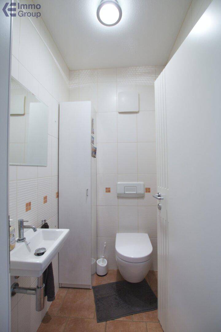 Kleines Gäste-WC mit wandhängender Toilette, Waschbecken und weißen Fliesen.