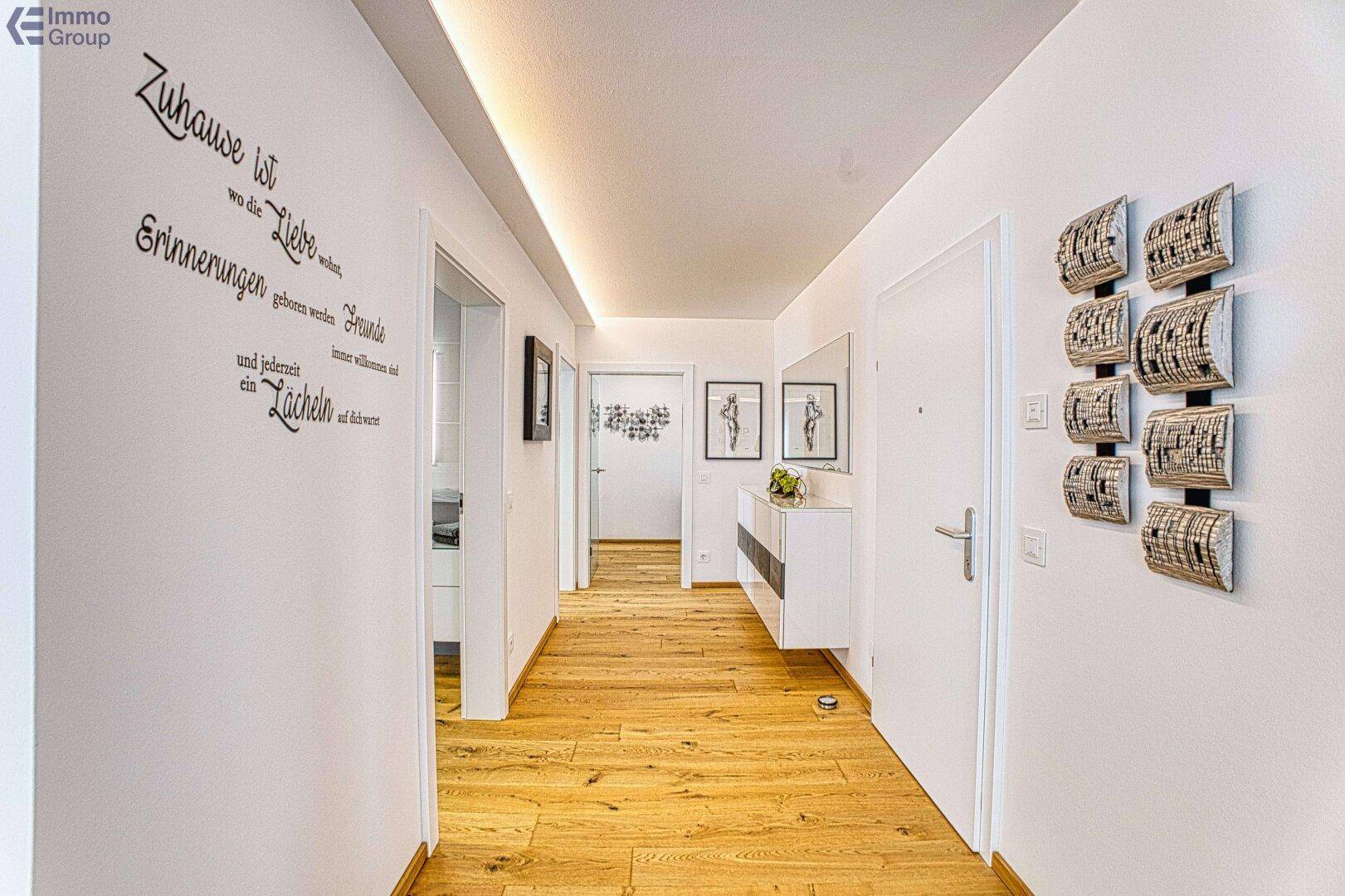 Heller Flur mit Holzboden, moderner Wanddekoration und Zugang zu weiteren Räumen.