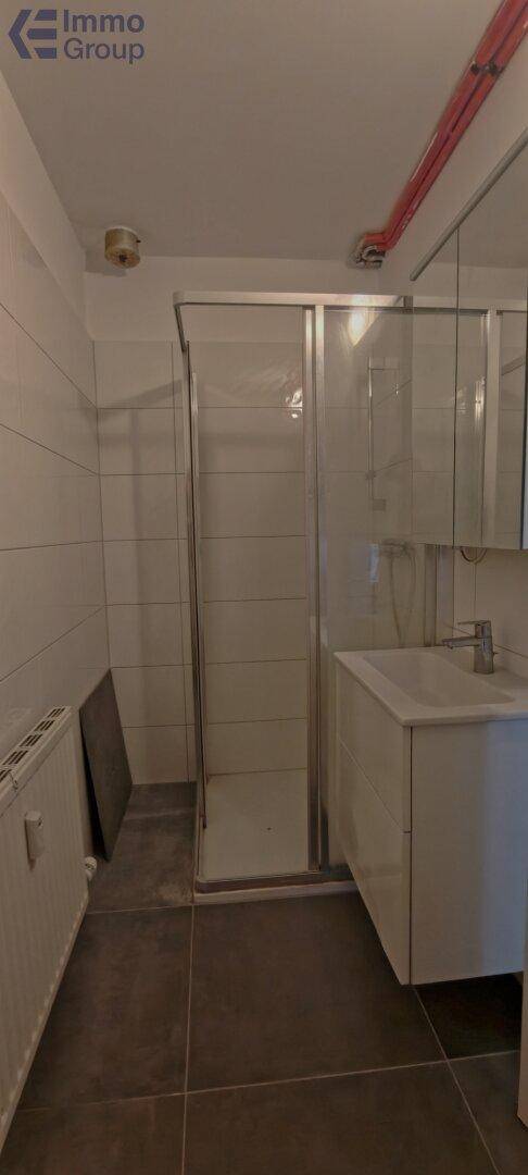 Modernes Badezimmer mit Duschkabine, Waschtisch und hellen Fliesen.