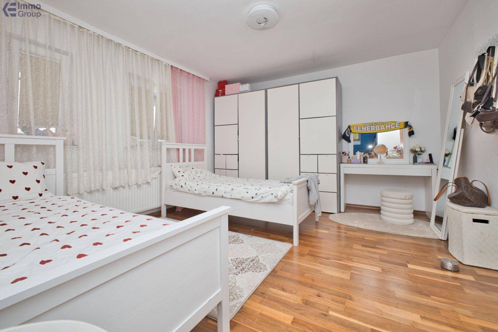 Schlafzimmer mit zwei Einzelbetten, großem Kleiderschrank, Schminktisch und Holzboden.