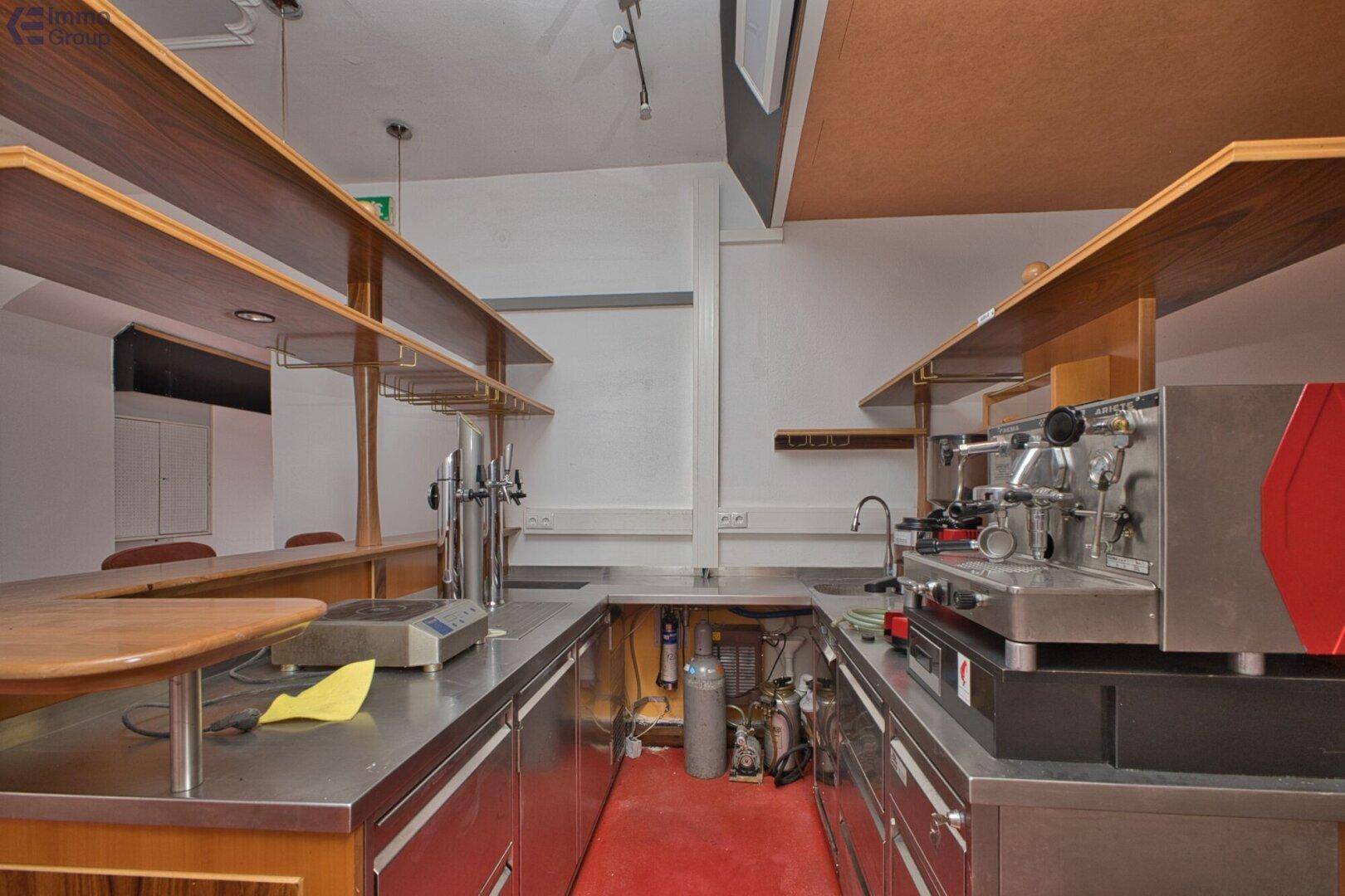 Detailansicht des Barbereichs mit Edelstahltheke, Zapfanlage und professioneller Kaffeemaschine.
