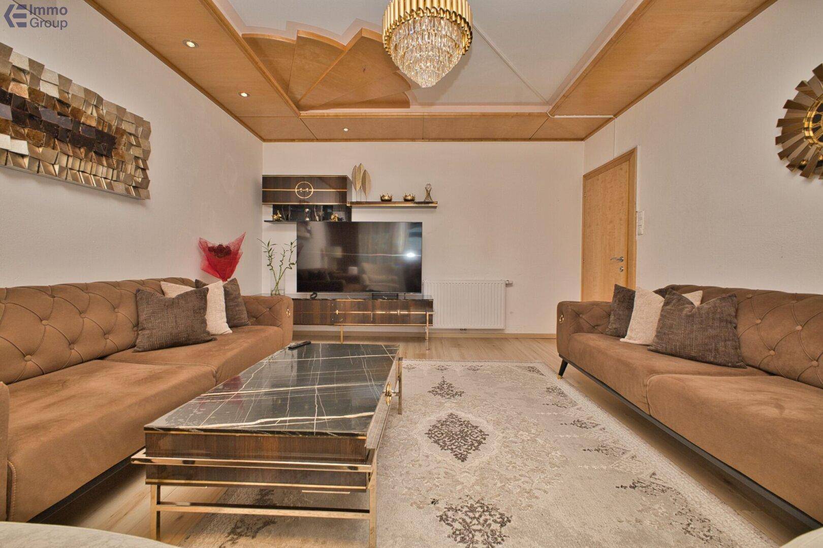 Gemütliches Wohnzimmer mit braunen Sofas, dekorativer Decke und modernem Couchtisch.