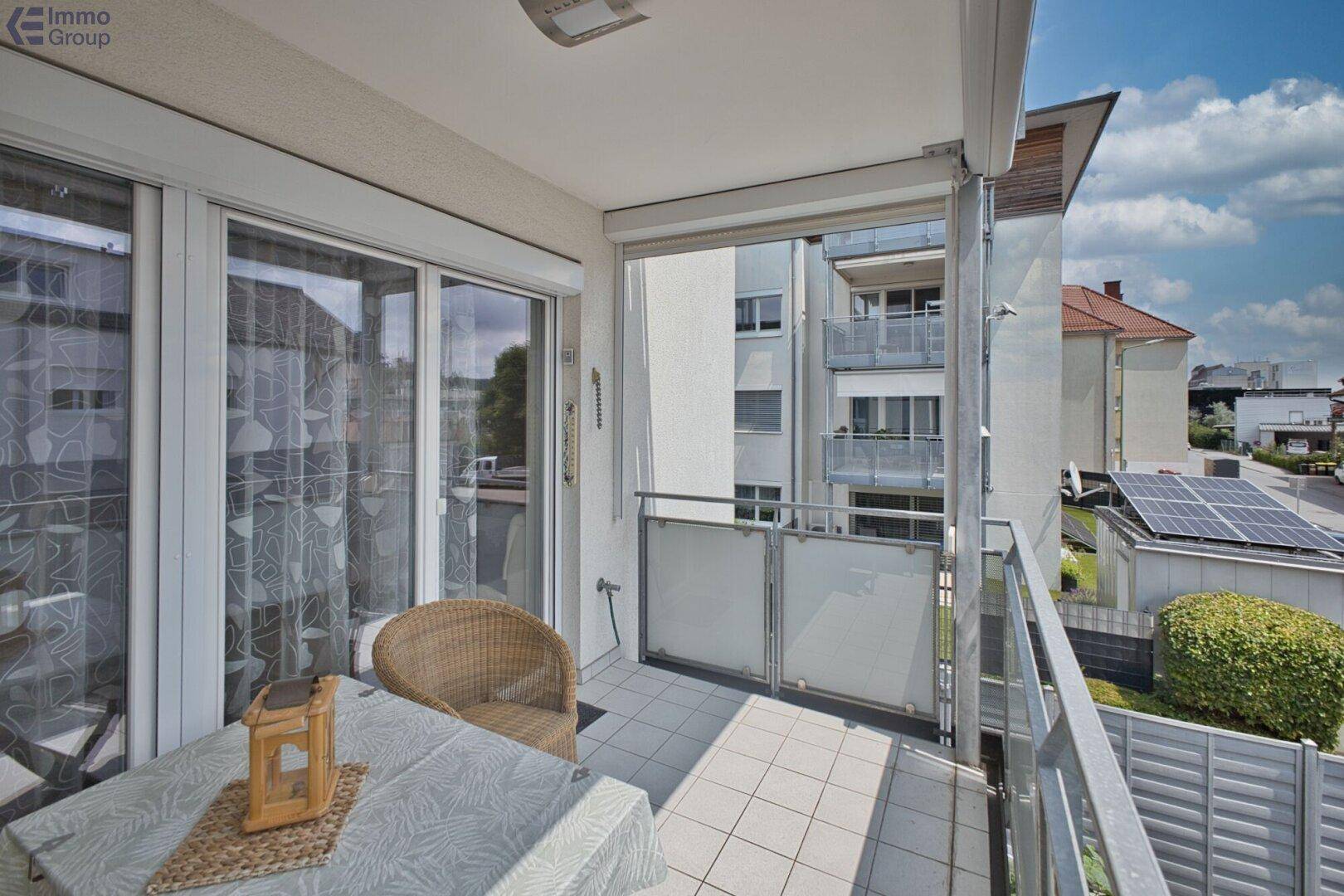 Möblierter Balkon mit Fliesenboden, Blick auf die Umgebung und Solaranlagen.