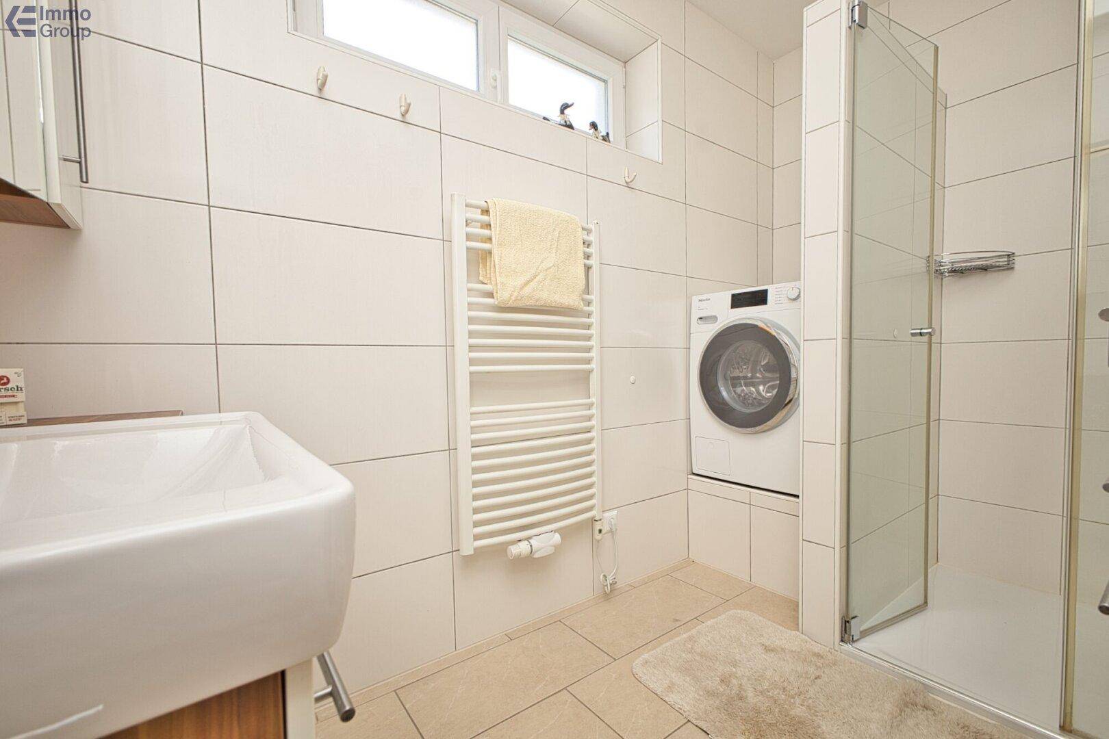 Modernes Badezimmer mit Duschkabine, Waschbecken und Handtuchheizkörper.