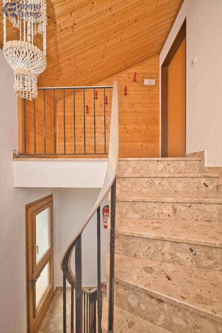 Treppenhaus mit Marmorstufen, Holzverkleidung und dekorativer Muschelleuchte.