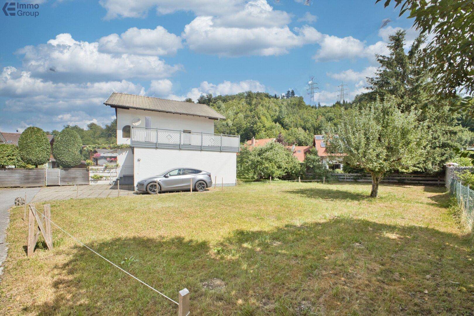 Großer Gartenbereich mit Rasenfläche, Bäumen und einem Haus im Hintergrund.