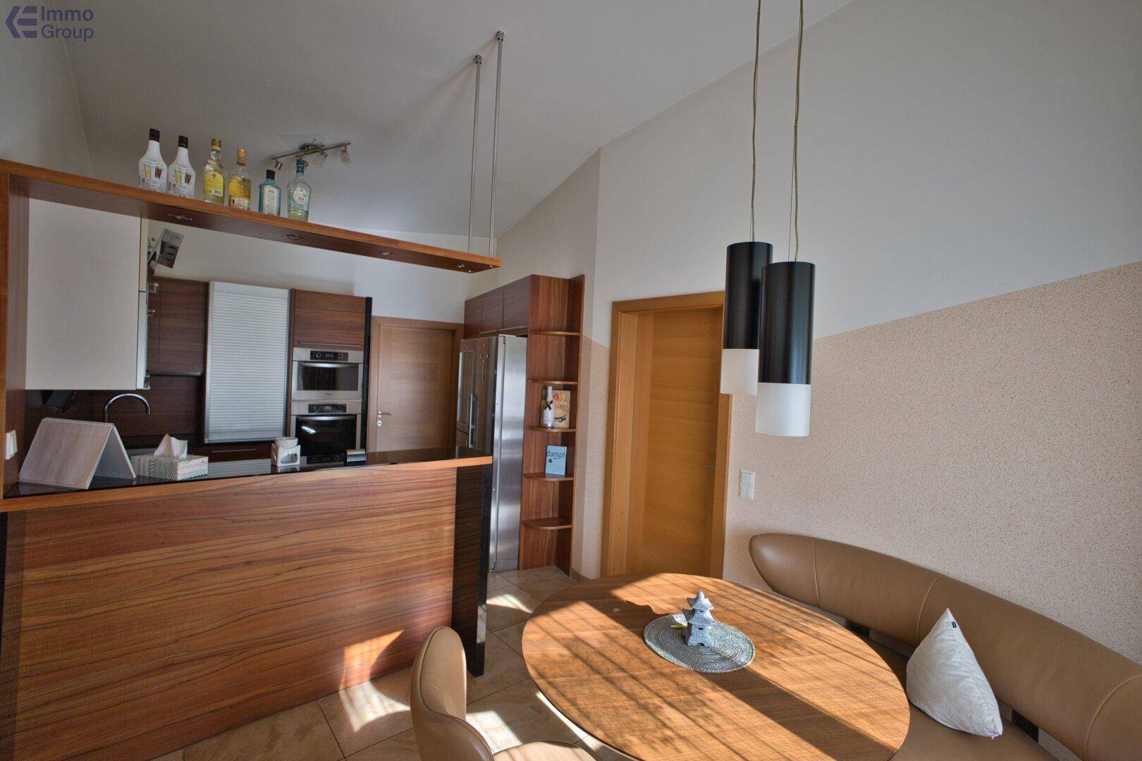 Moderne Holzküche mit integrierten Geräten und einem gemütlichen Essbereich mit Sitzbank.