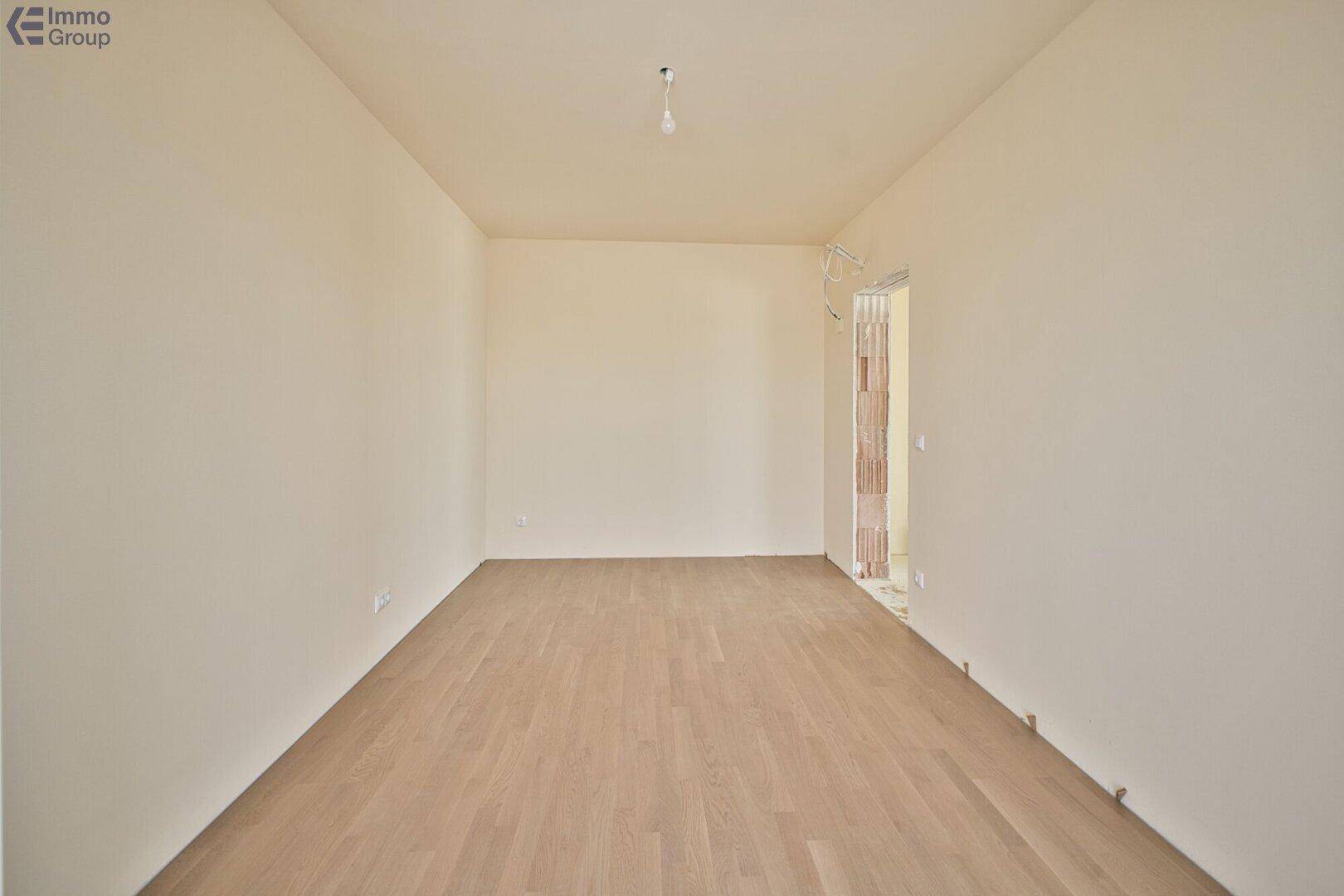 Heller, leerer Raum mit hellem Holzparkett und Zugang zu einem Außenbereich, bereit zur individuellen Gestaltung.
