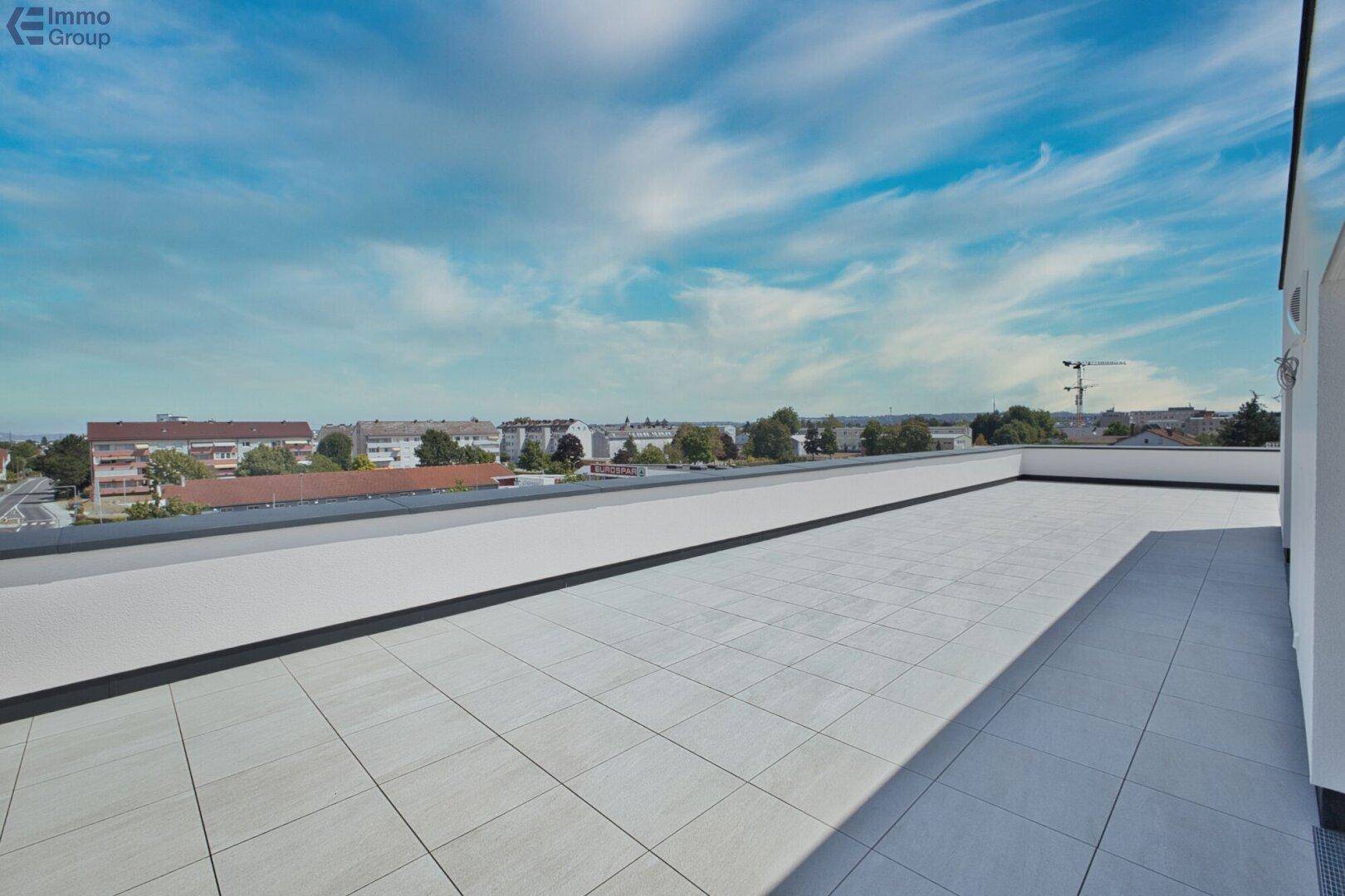 Weitläufige Dachterrasse mit Fliesenboden und Panoramablick über die Stadtlandschaft.