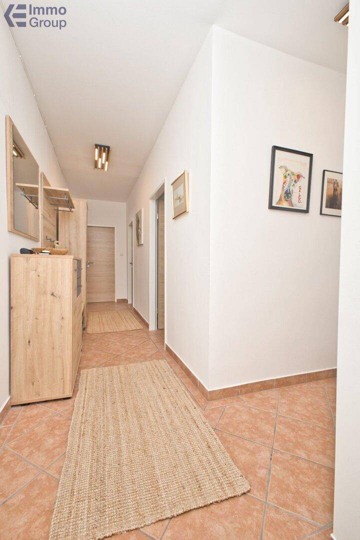 Heller Flur mit Terrakotta-Fliesenboden und Holzmöbeln, der zu weiteren Räumen führt.