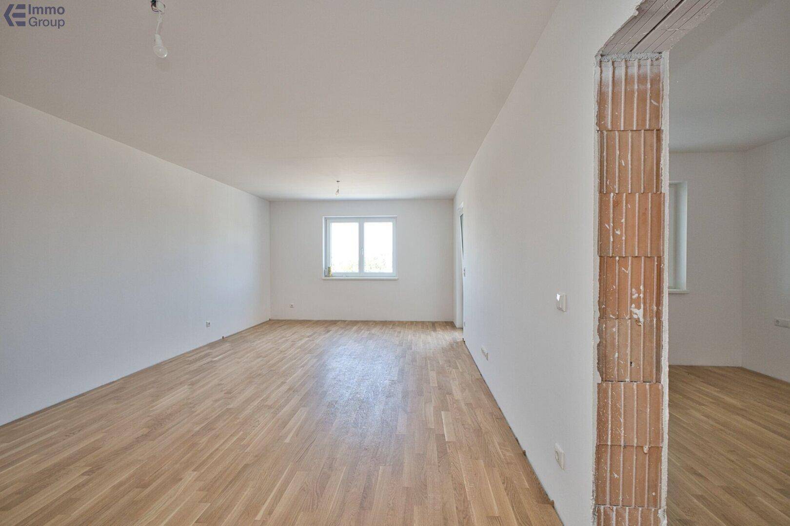 Leeres Zimmer mit hellem Holzfußboden und weißen Wänden, ideal als Kinder- oder Gästezimmer.