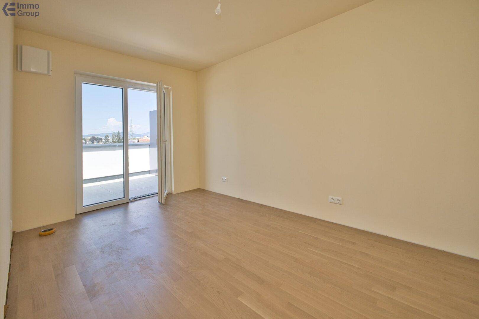Helles Zimmer mit Parkettboden und Zugang zu einem Außenbereich, ideal als Schlafzimmer.