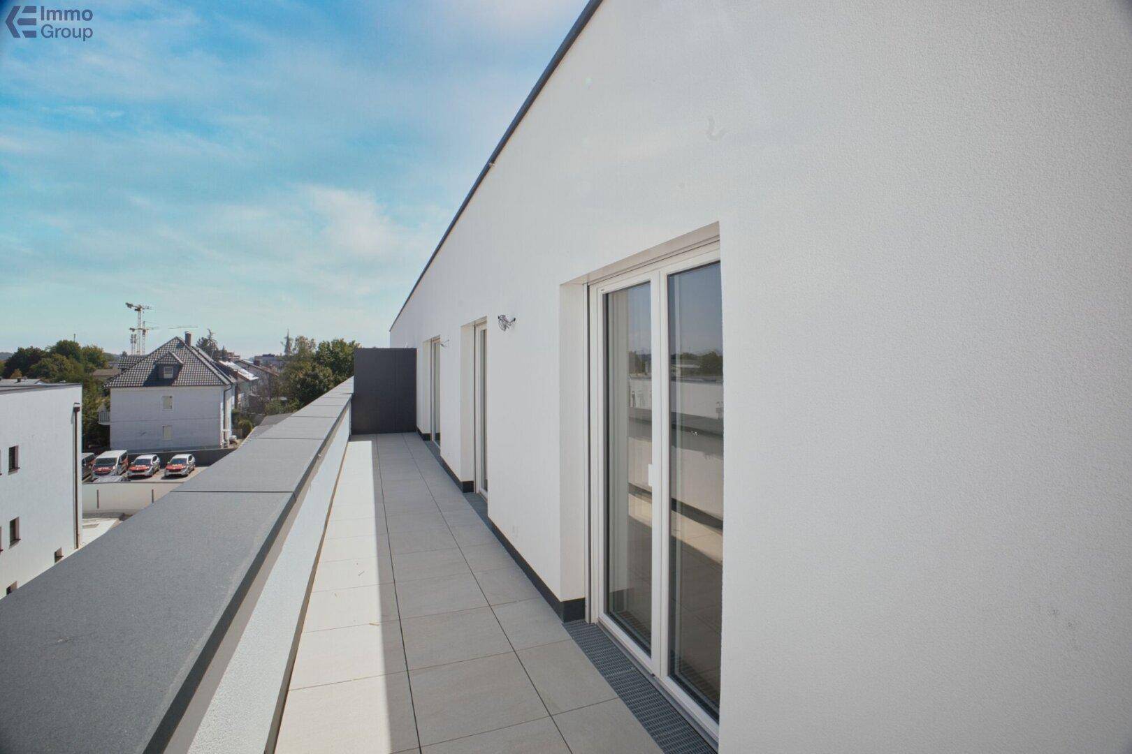 Geräumiger Balkon mit Fliesenboden und weitem Blick auf die städtische Umgebung.