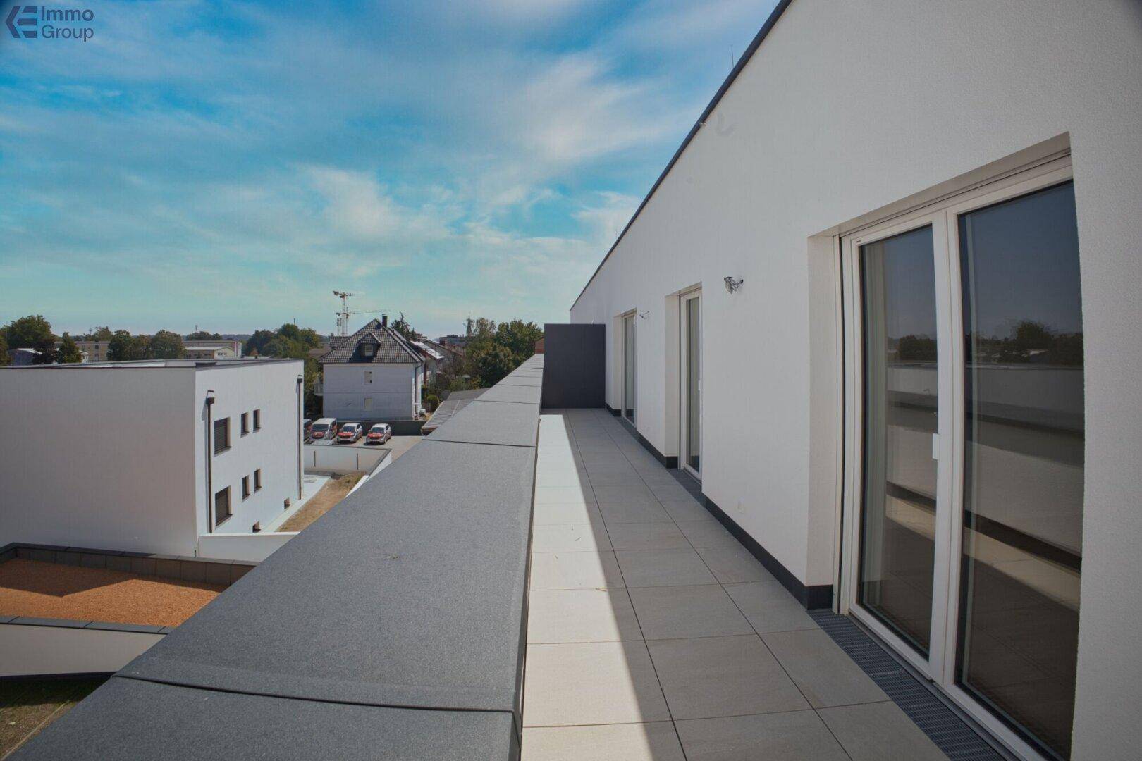 Langer Balkon mit Fliesenboden und weitem Blick auf die umliegende Bebauung.