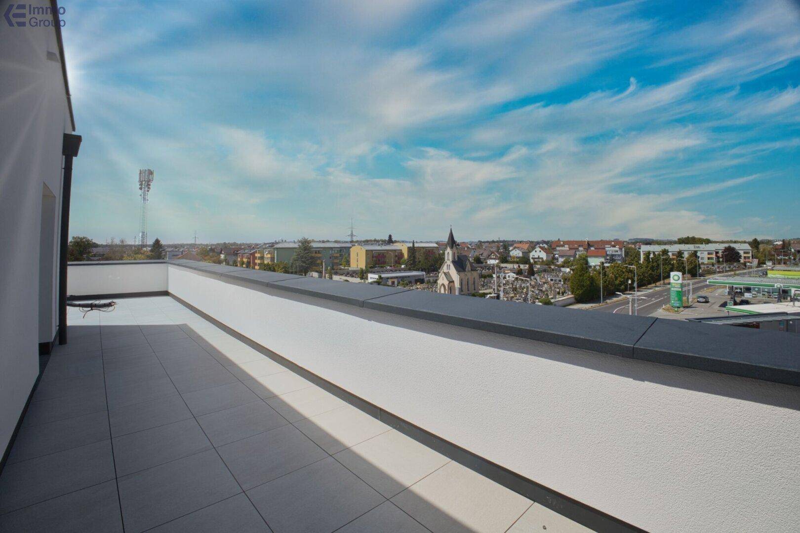 Weitläufige Dachterrasse mit Fliesenboden und Panoramablick über die Stadt und die umliegende Landschaft.