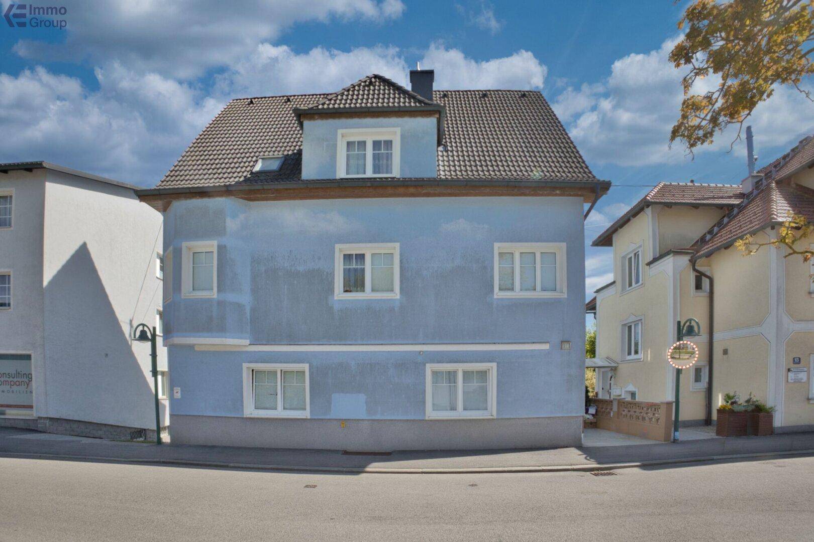 Straßenansicht des blauen Einfamilienhauses mit traditionellem Satteldach.