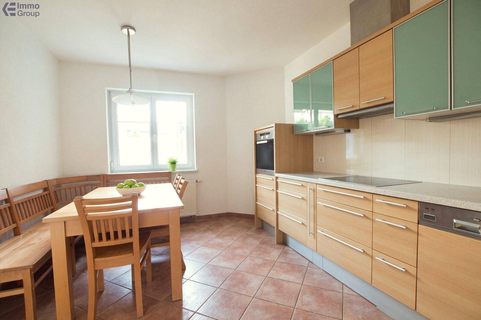 Geräumige Wohnküche mit Holzeinbauten, Essbereich und Fenster.