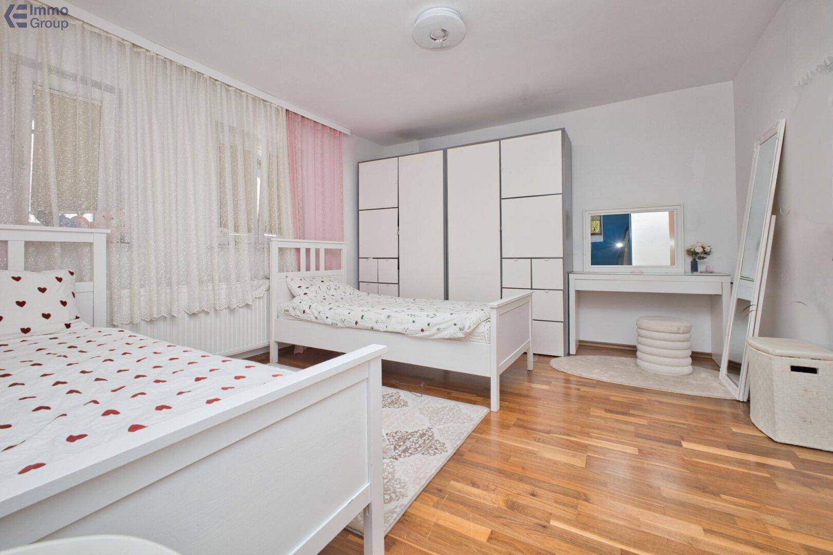 Kinderzimmer mit zwei Einzelbetten, Holzfußboden und großem Kleiderschrank.