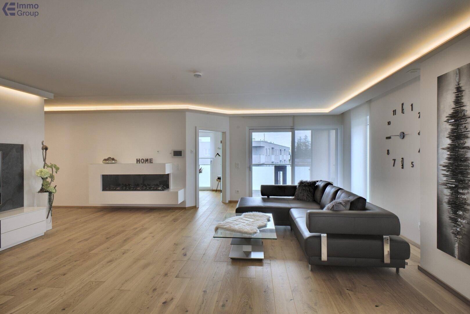 Modernes Wohnzimmer mit gemütlichem Sofa, elegantem Kamin und Zugang zu einem Balkon.