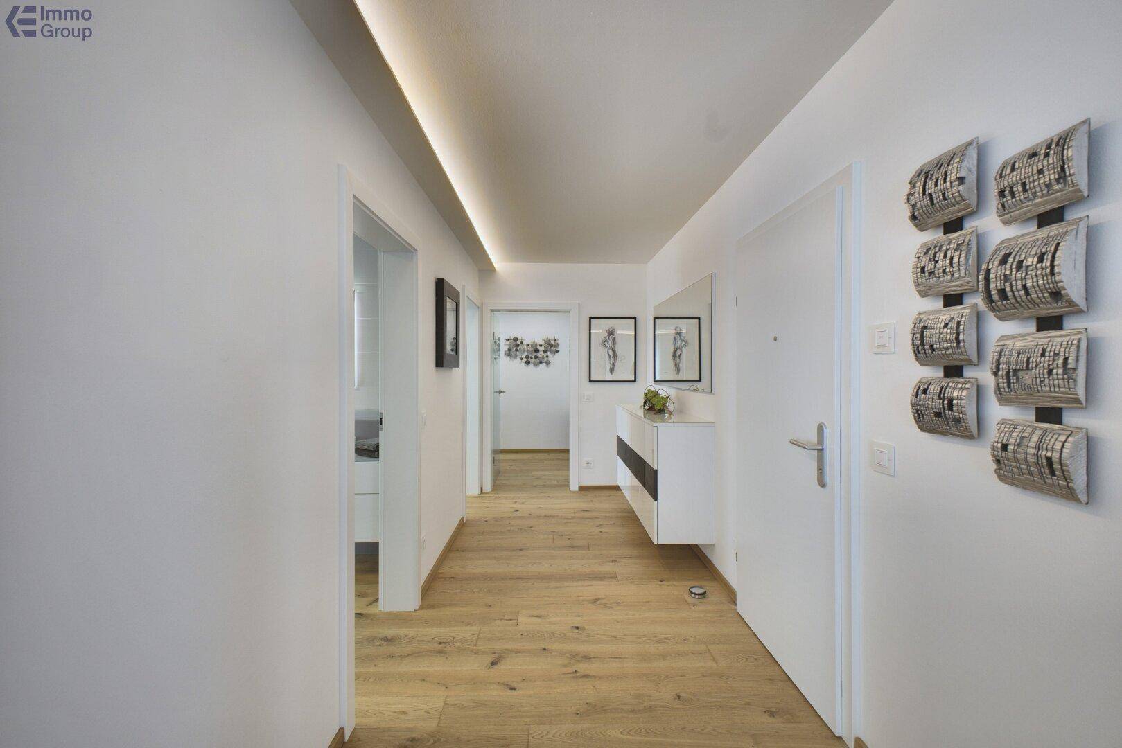 Langer, heller Flur mit Holzboden und modernen Wanddekorationen.