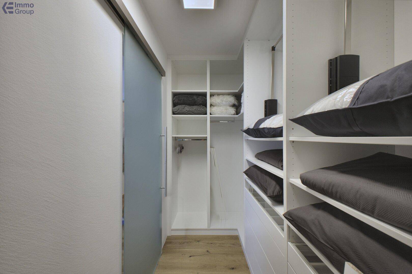 Praktischer begehbarer Kleiderschrank mit viel Stauraum und Schiebetür.