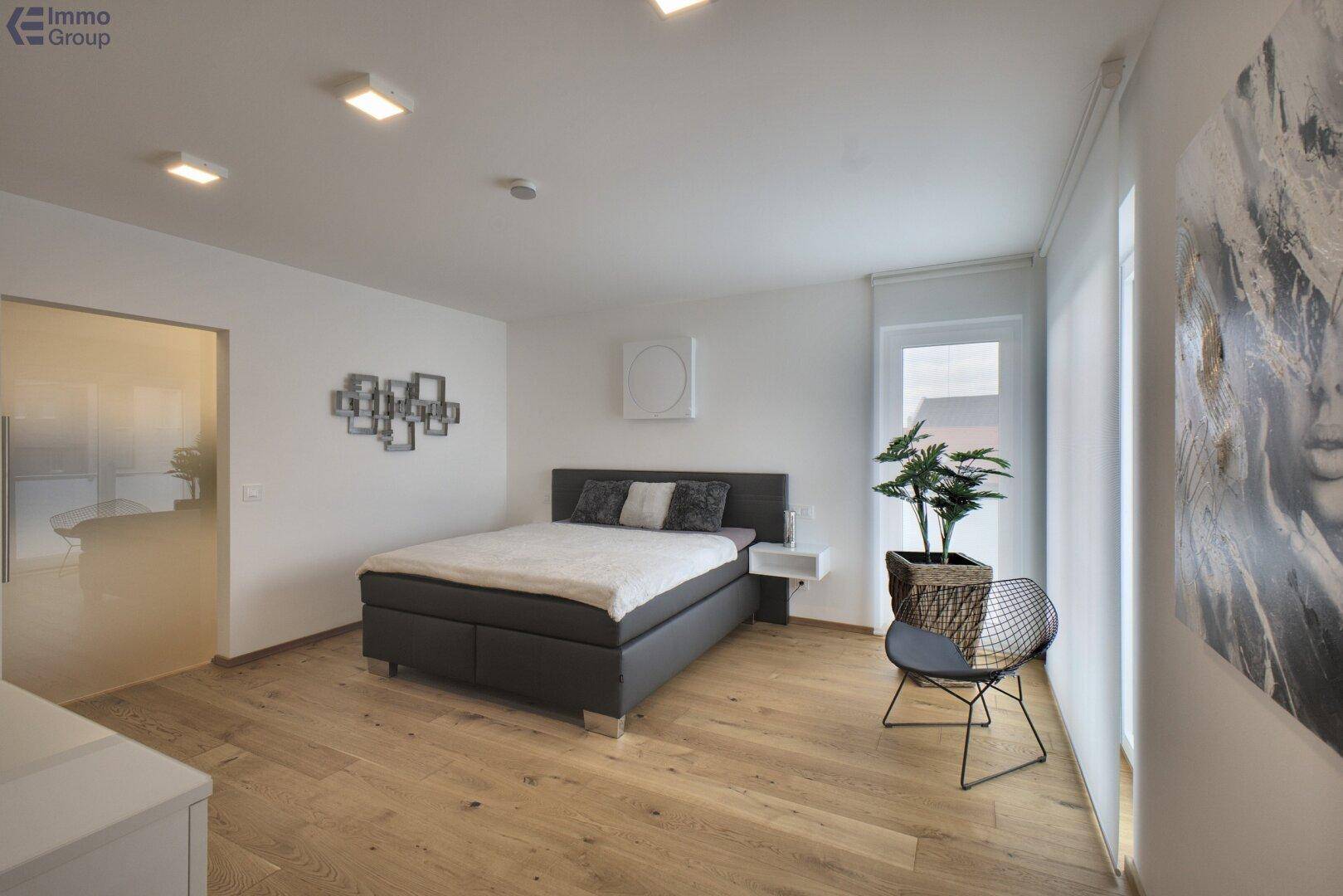 Modernes Schlafzimmer mit Doppelbett, Holzboden und großem Fenster.