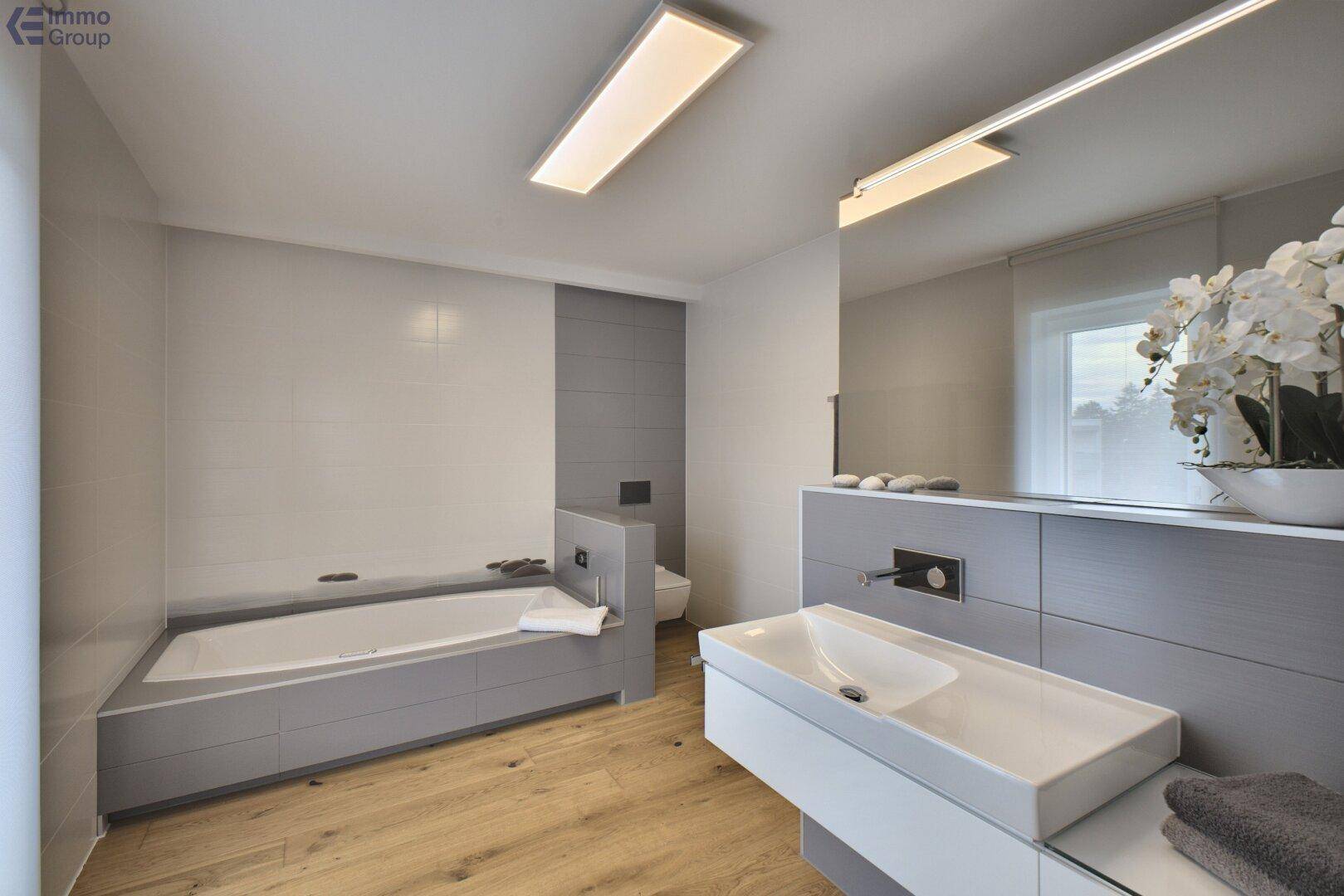 Modernes Badezimmer mit Badewanne, stilvollem Waschbecken und Holzboden.