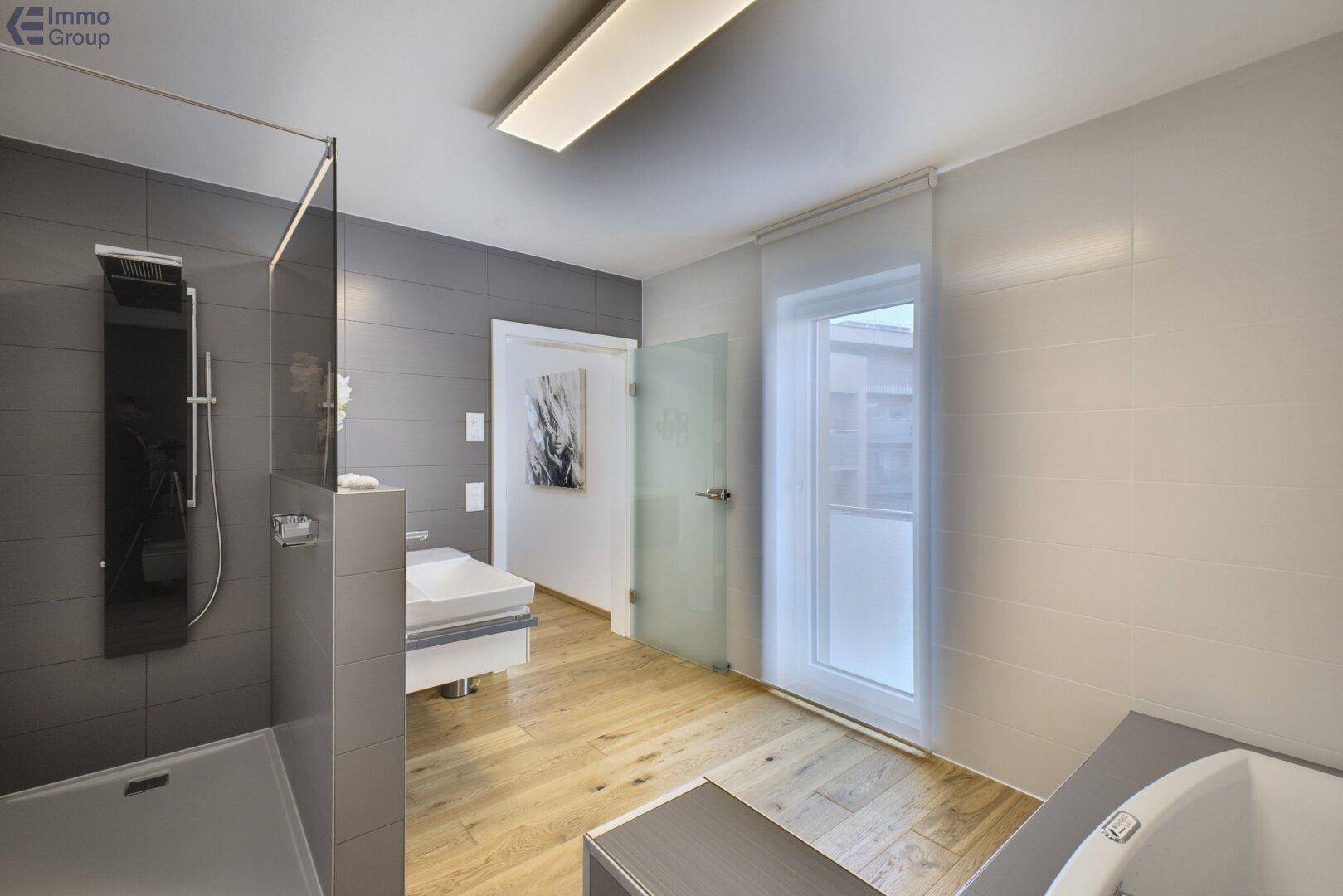 Helles Badezimmer mit moderner Dusche, Fenster und Holzboden.