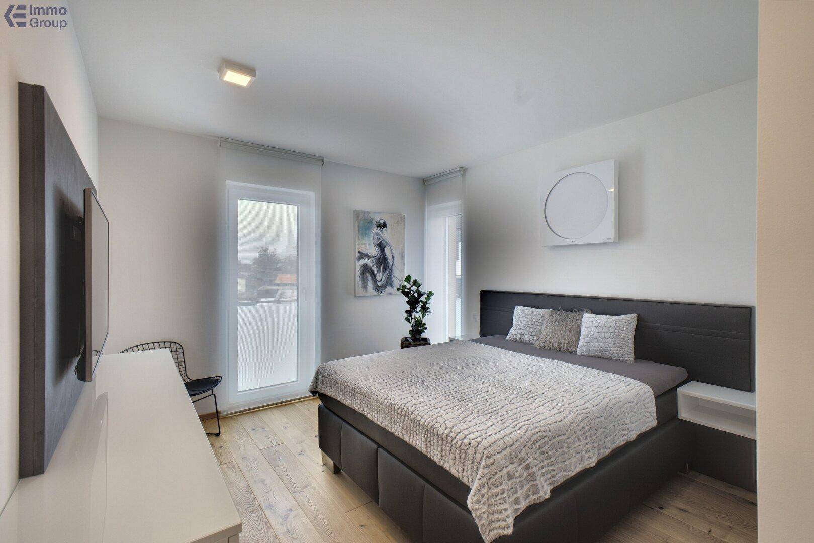 Helles Schlafzimmer mit Doppelbett, Holzboden und moderner Wanddekoration.