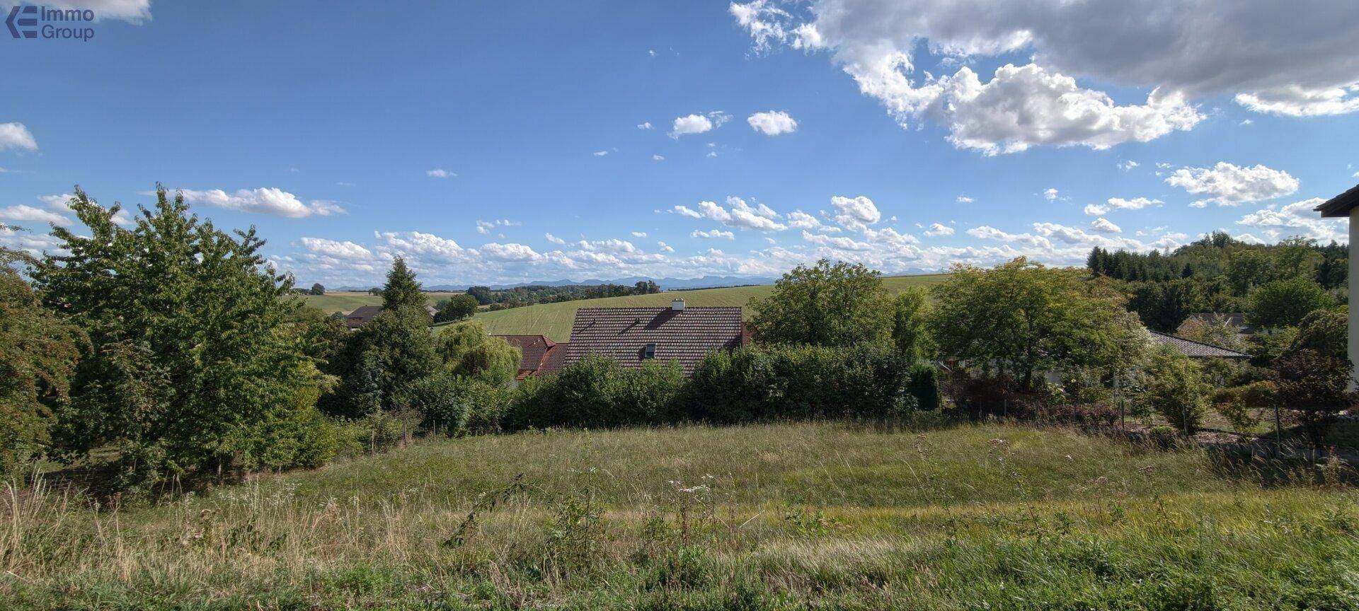 Malerische Aussicht auf eine ländliche Umgebung mit Bäumen und einem Haus unter einem weiten Himmel.