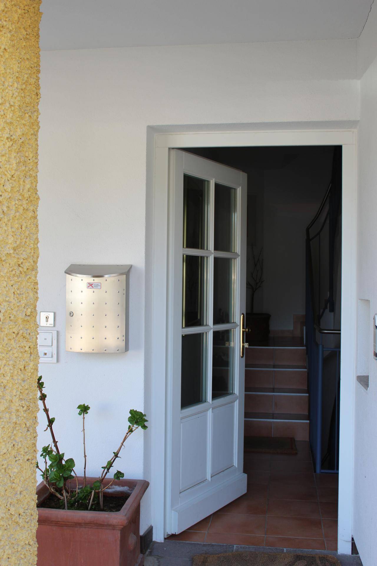 Heller Eingangsbereich mit weißer Tür und Blick auf die Treppe.