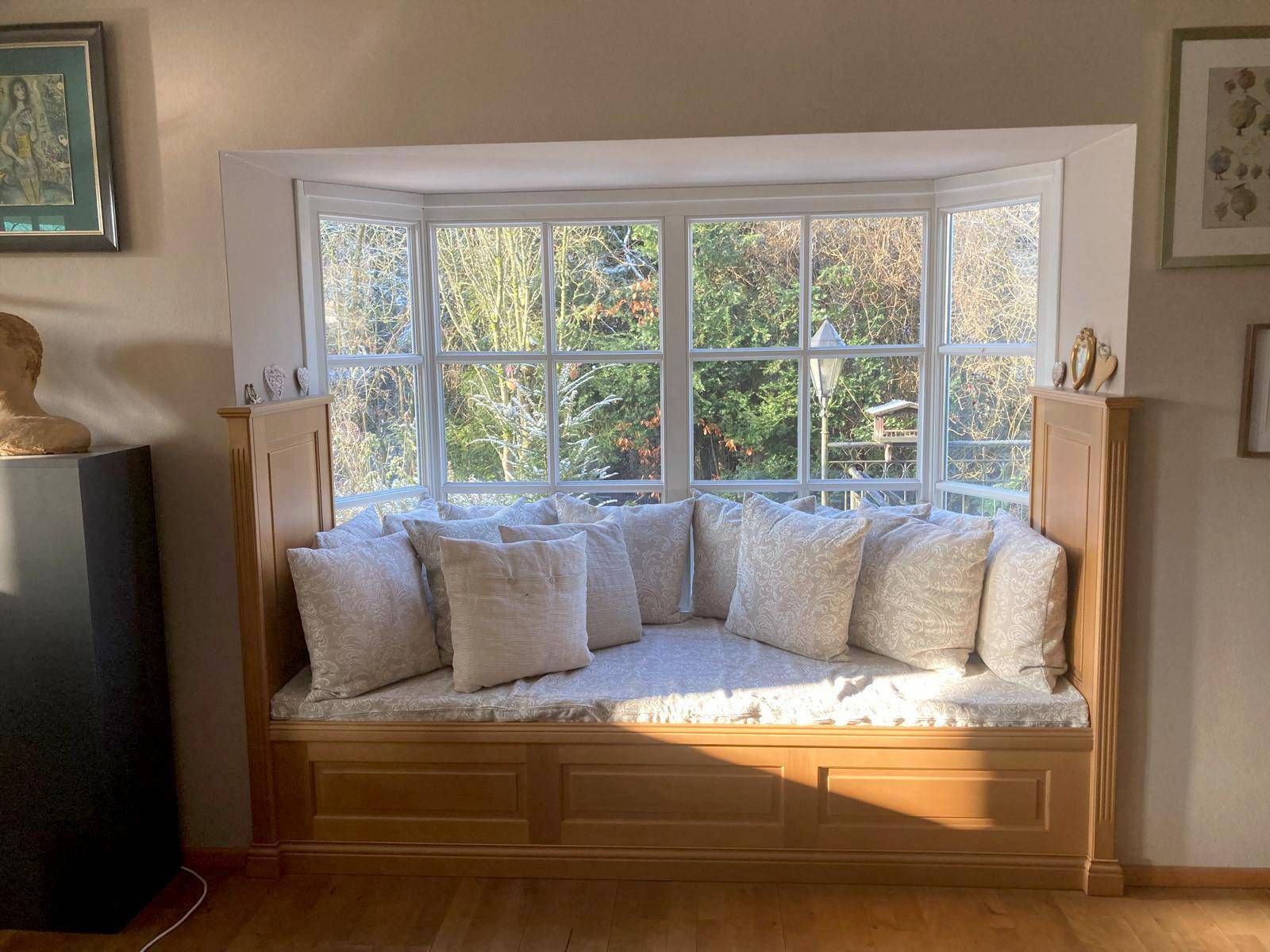 Gemütliche Fensterbank mit Kissen und Blick in den grünen Garten.