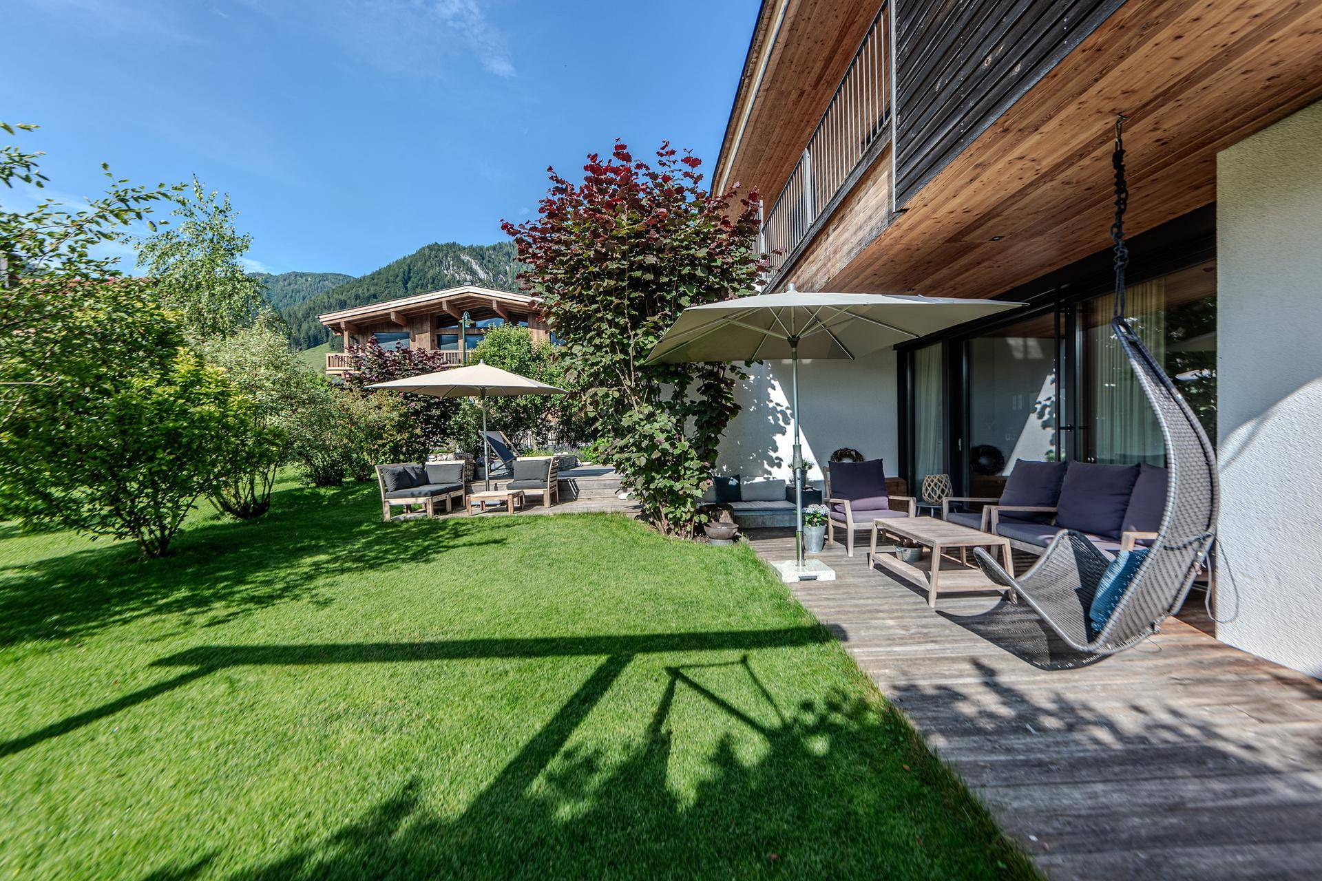 Sonnige Terrasse mit bequemen Gartenmöbeln und direktem Zugang zum grünen Rasenbereich.
