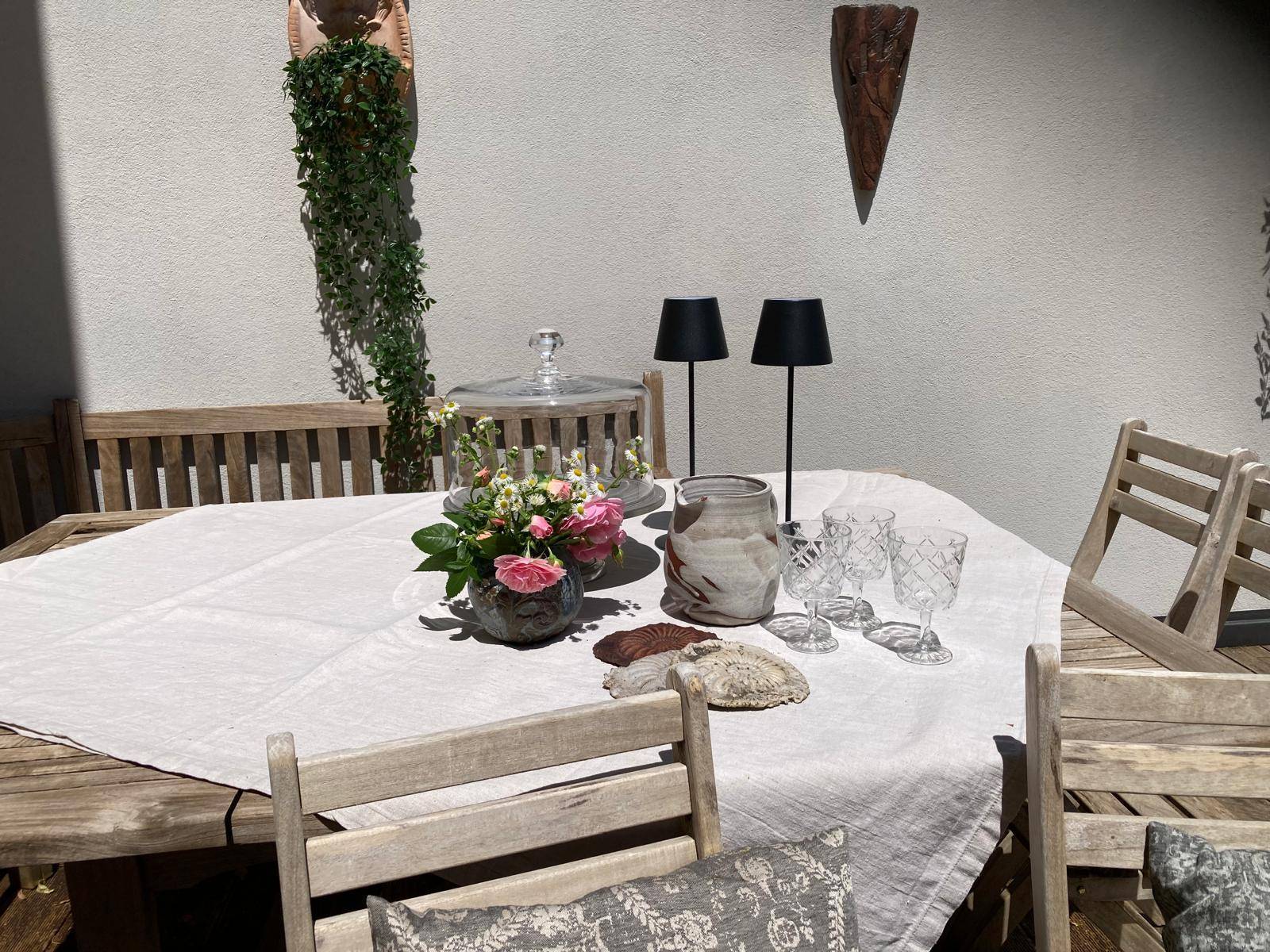 Detailansicht des Esstisches auf der Terrasse mit Dekoration und Geschirr.