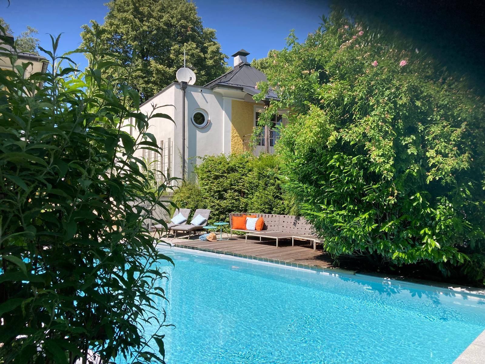 Entspannender Poolbereich mit Liegestühlen und üppiger Vegetation.