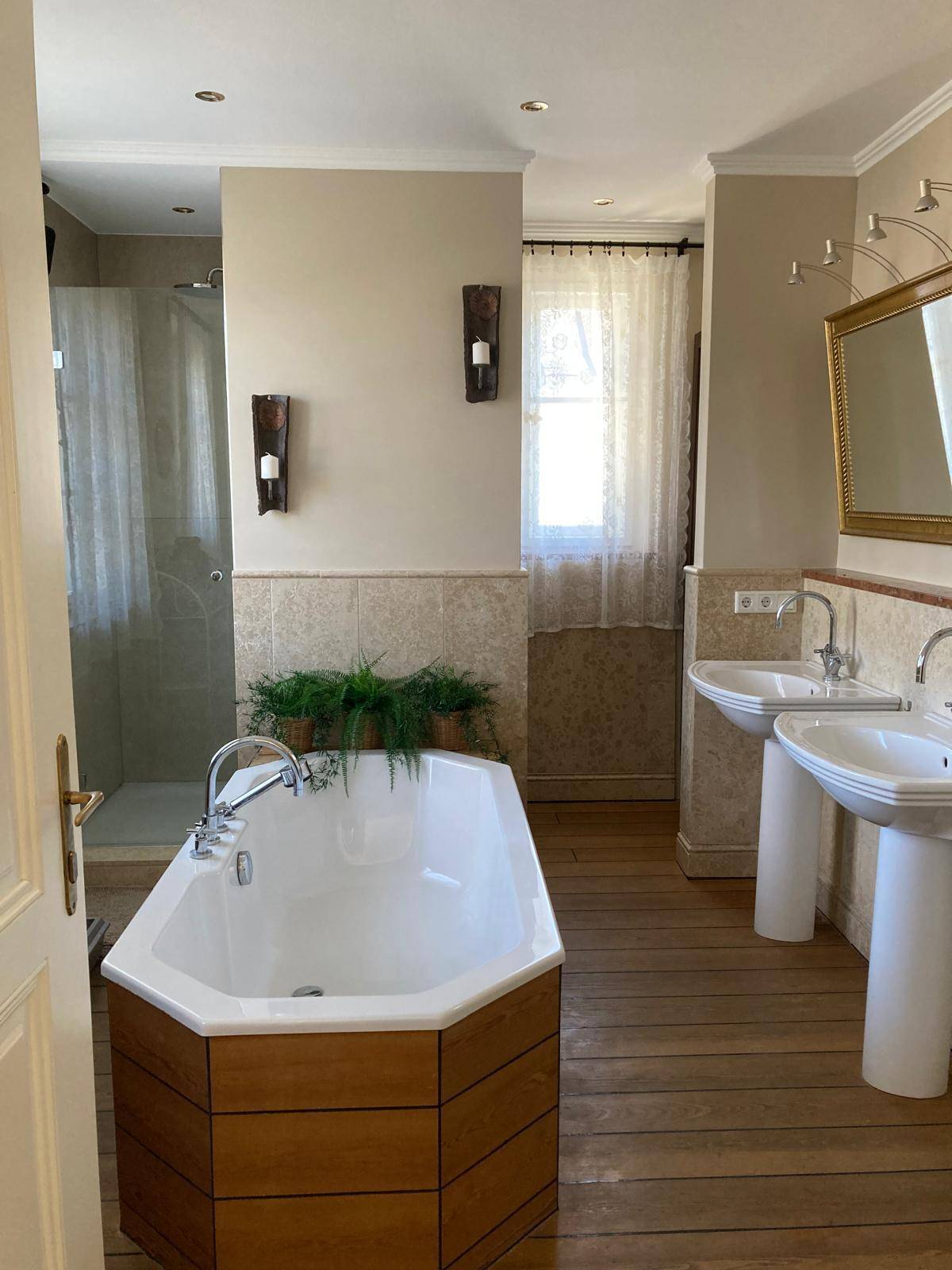 Geräumiges Badezimmer mit Badewanne, zwei Waschbecken und separater Dusche.