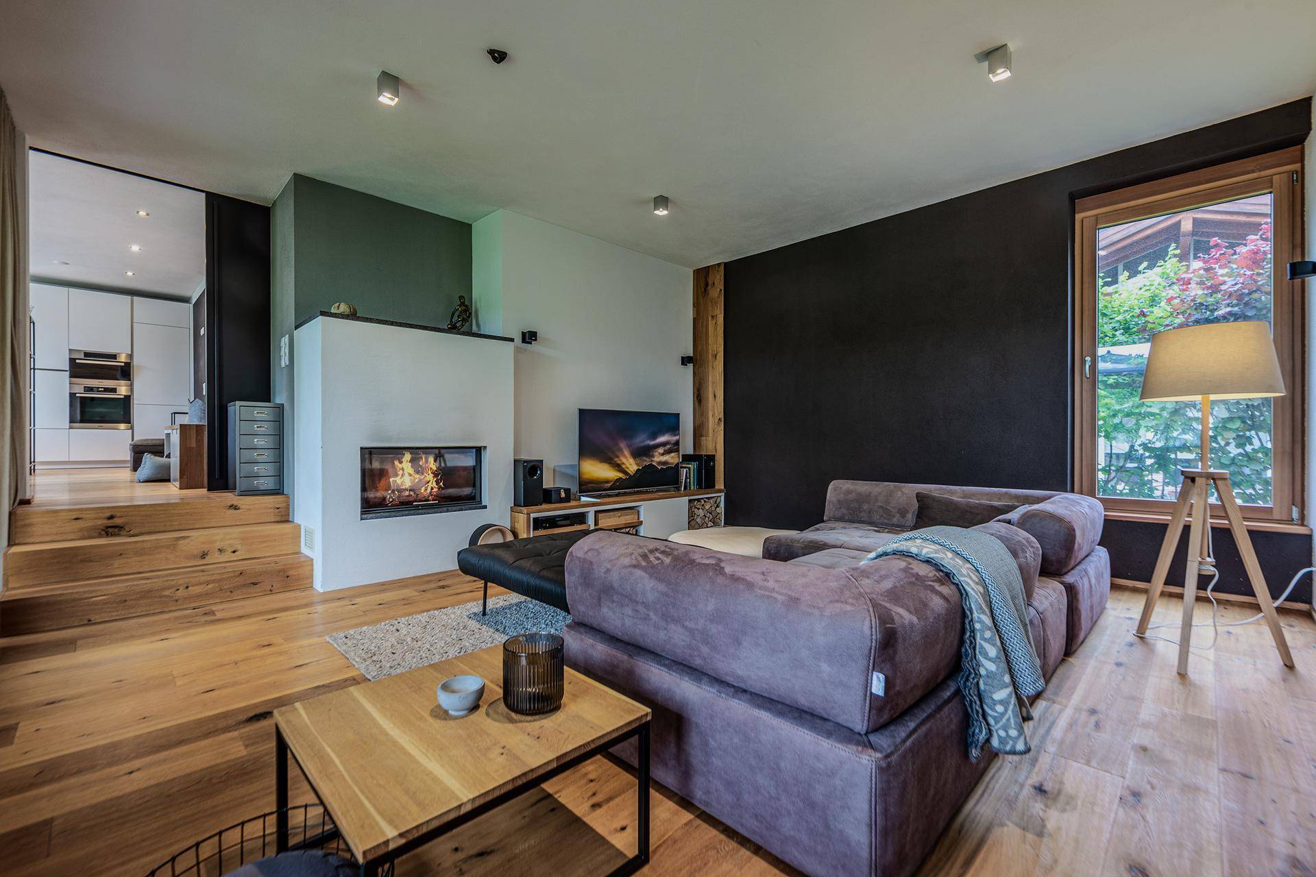 Gemütliches Wohnzimmer mit Kamin, großem Sofa und Holzboden, mit direktem Zugang zur Terrasse.