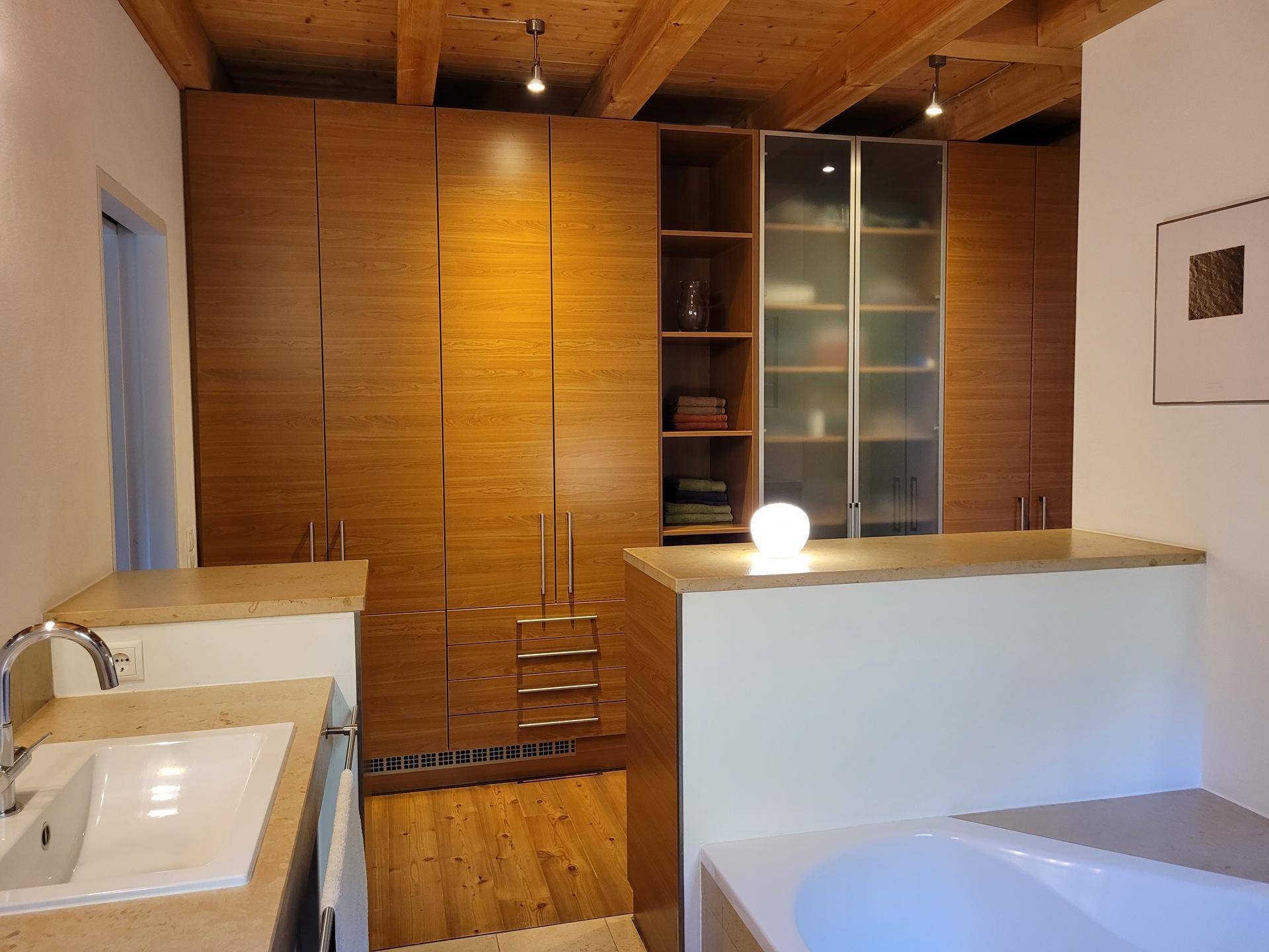Geräumiges Badezimmer mit Badewanne und integrierten Holzschränken, die viel Stauraum bieten.