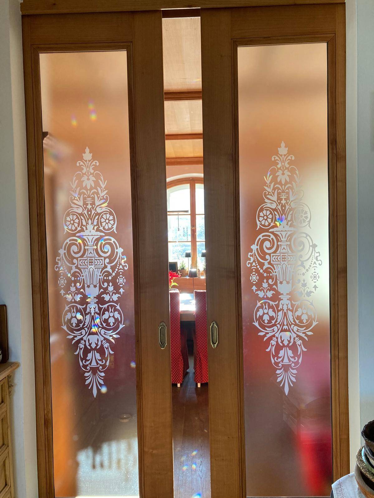 Elegante Schiebetüren mit Glas und Ornamenten, die zum Esszimmer führen.
