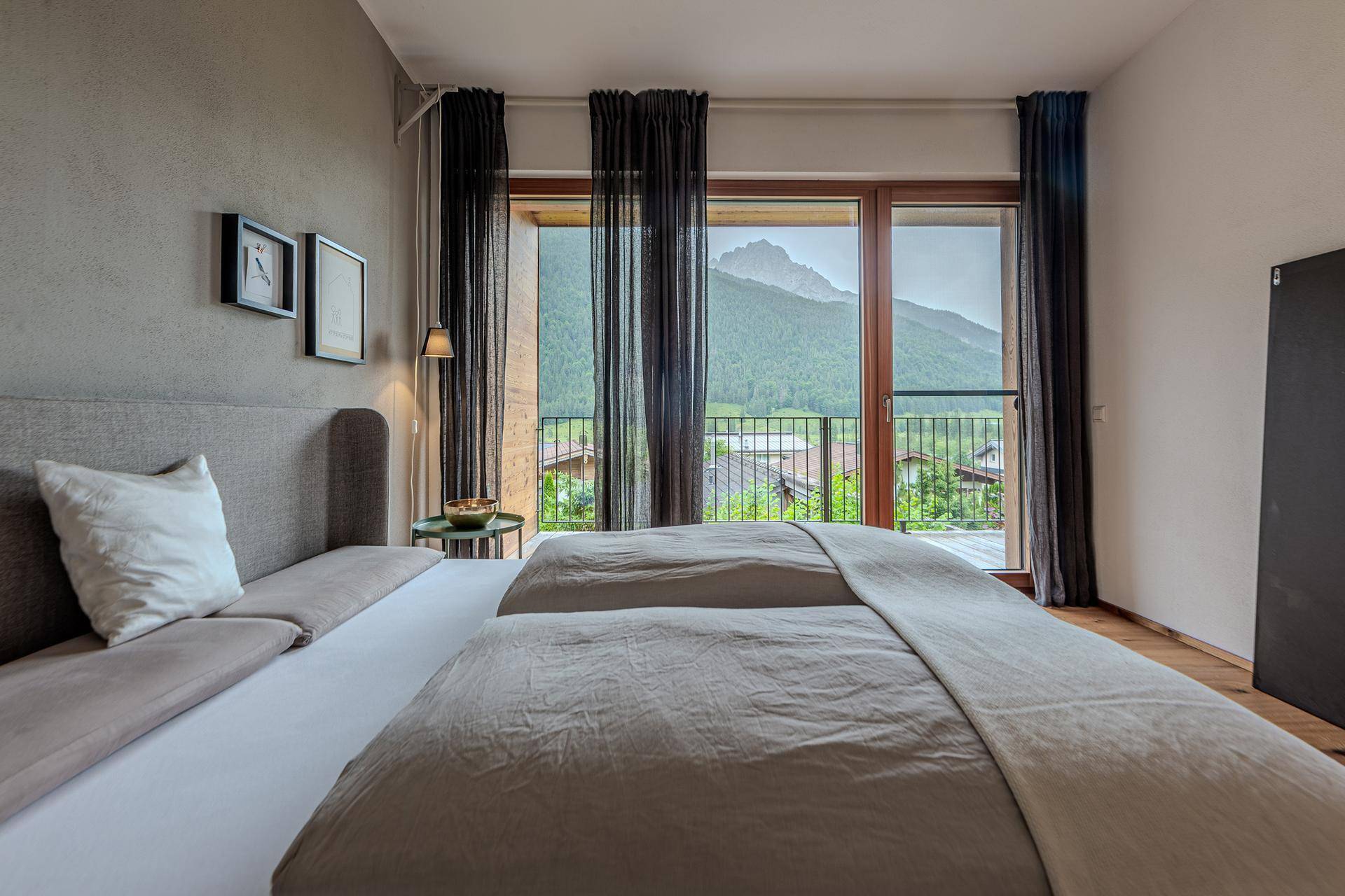 Helles Schlafzimmer mit komfortablem Bett und direktem Zugang zum Balkon mit Bergsicht.