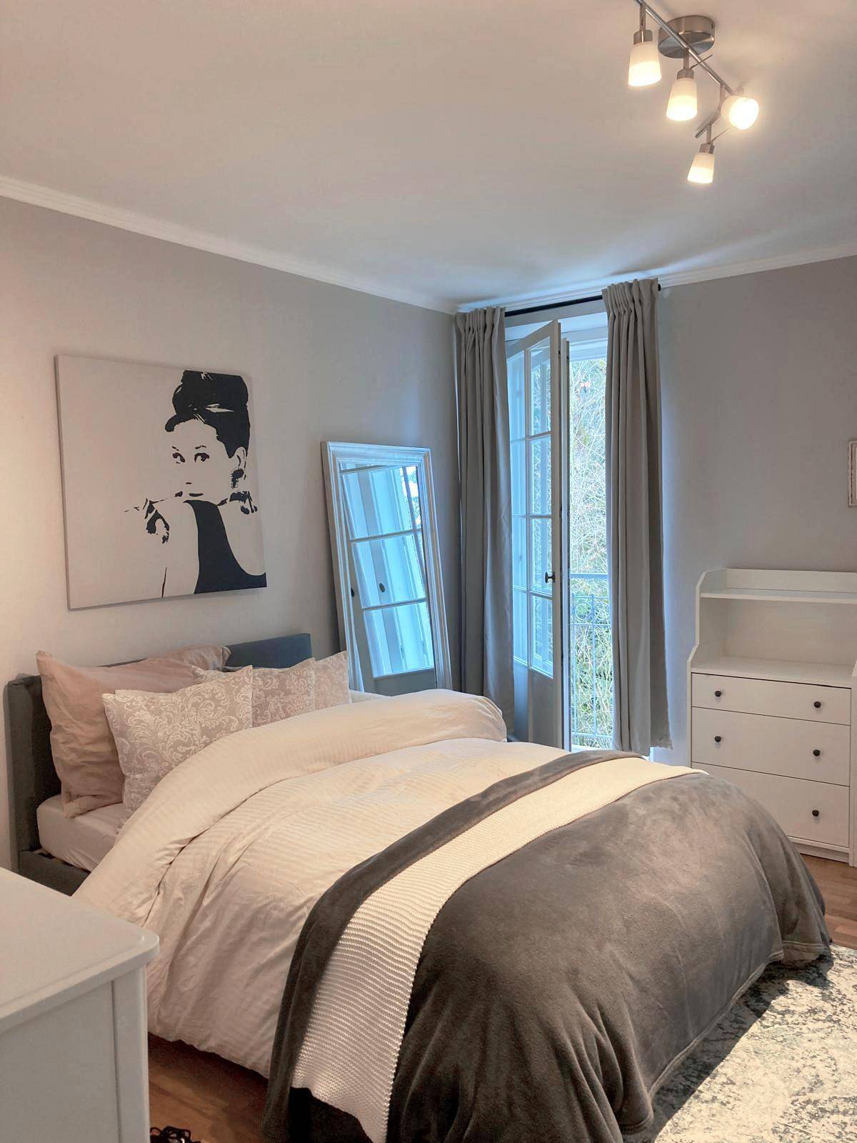 Modern eingerichtetes Schlafzimmer mit Doppelbett, Spiegel und Zugang zum französischen Balkon.
