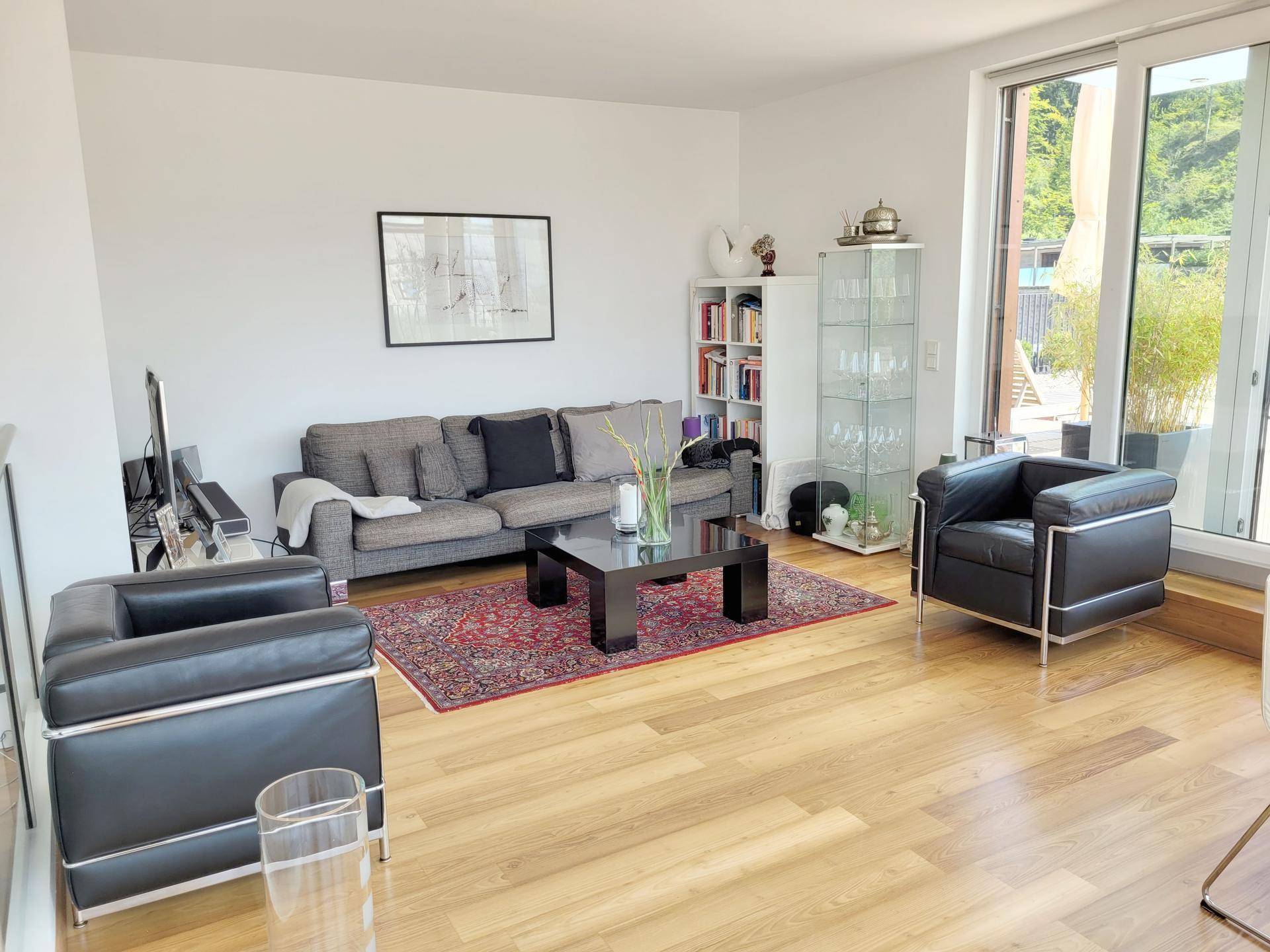 Helles Wohnzimmer mit Parkettboden, bequemen Sofas und Zugang zur Terrasse.